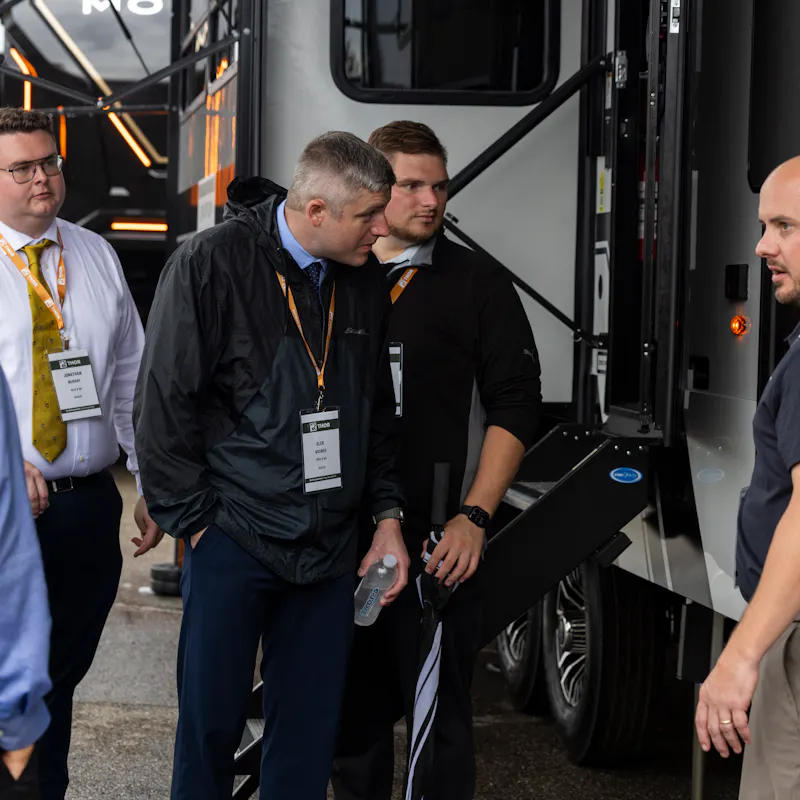 an RV salesman showing off features of an RV to dealers