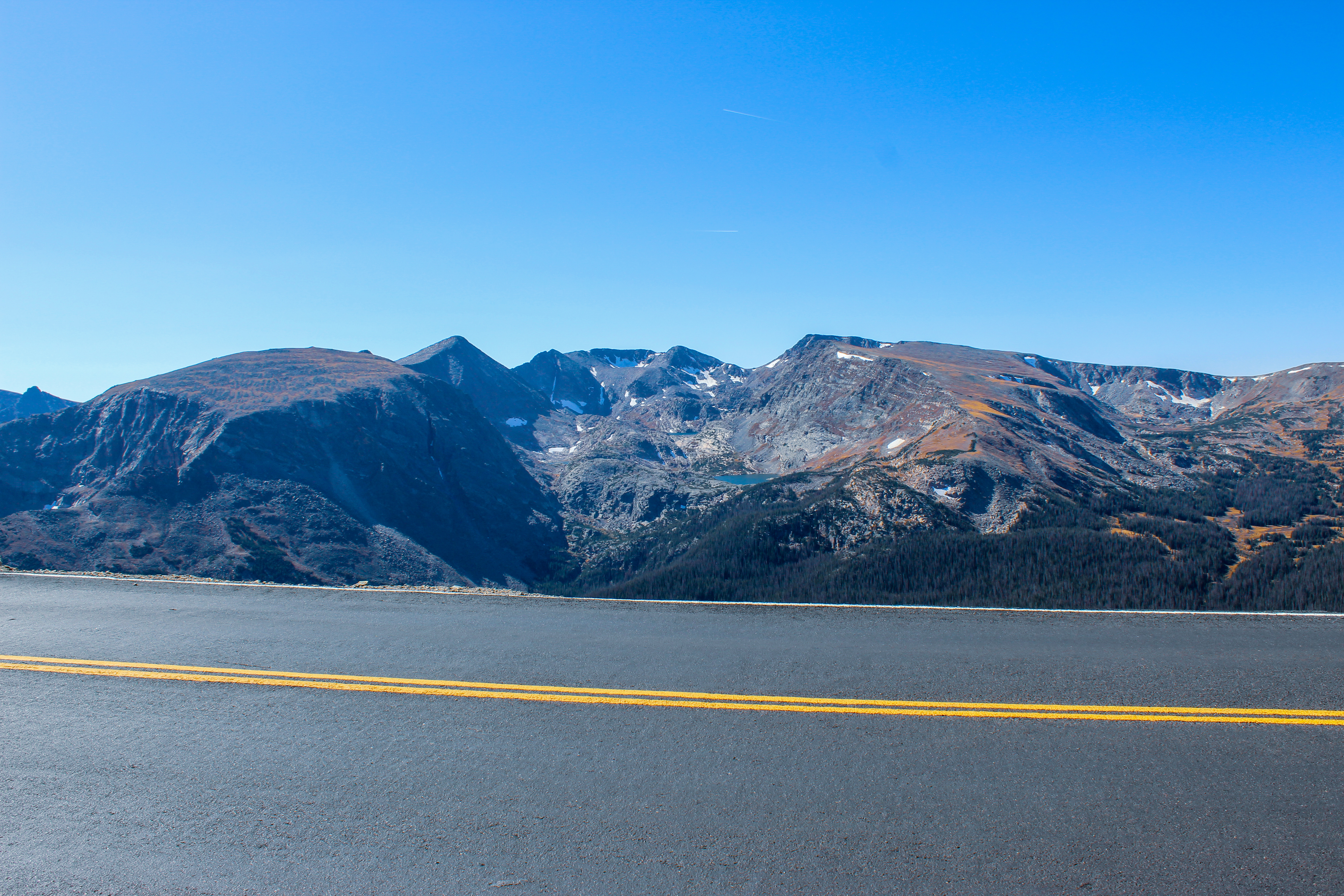Tall mountain peaks with some pockets of snow and a blue lake in Rocky Mountain National Park