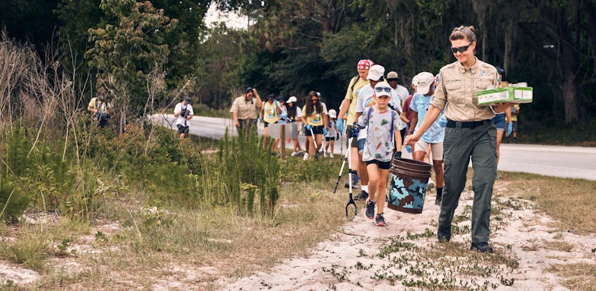 A park ranger leading girl scouts during a park pickup event
