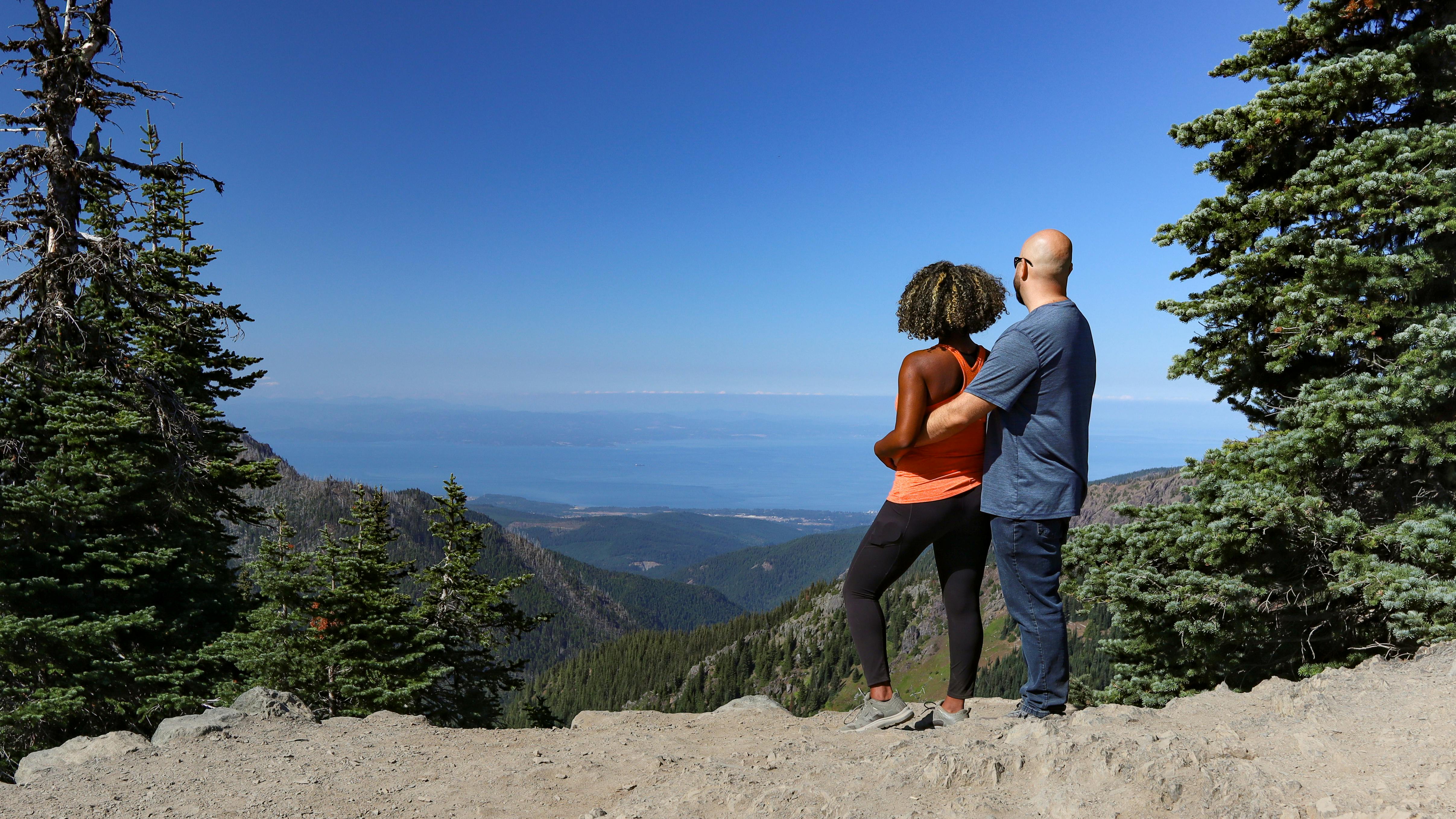 Gabe and Rocio looking out at an overlook of mountains and a lake