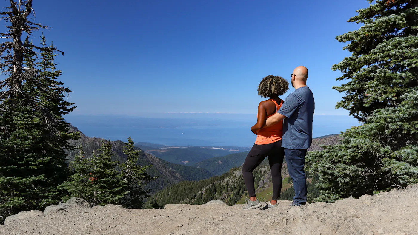 Gabe and Rocio looking out at an overlook of mountains and a lake