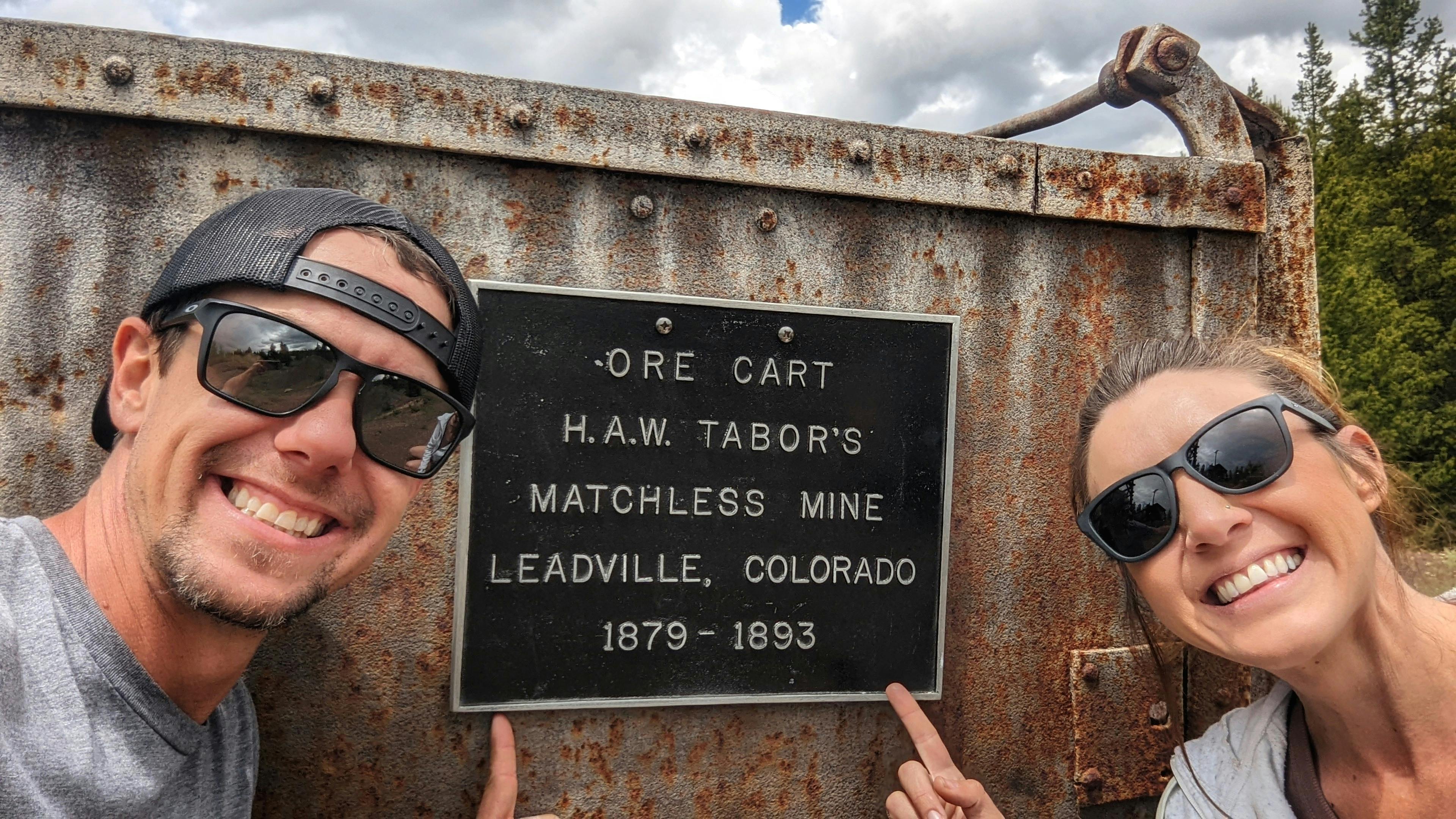 Dustin and Sarah Bauer pointing at a sign and smiling