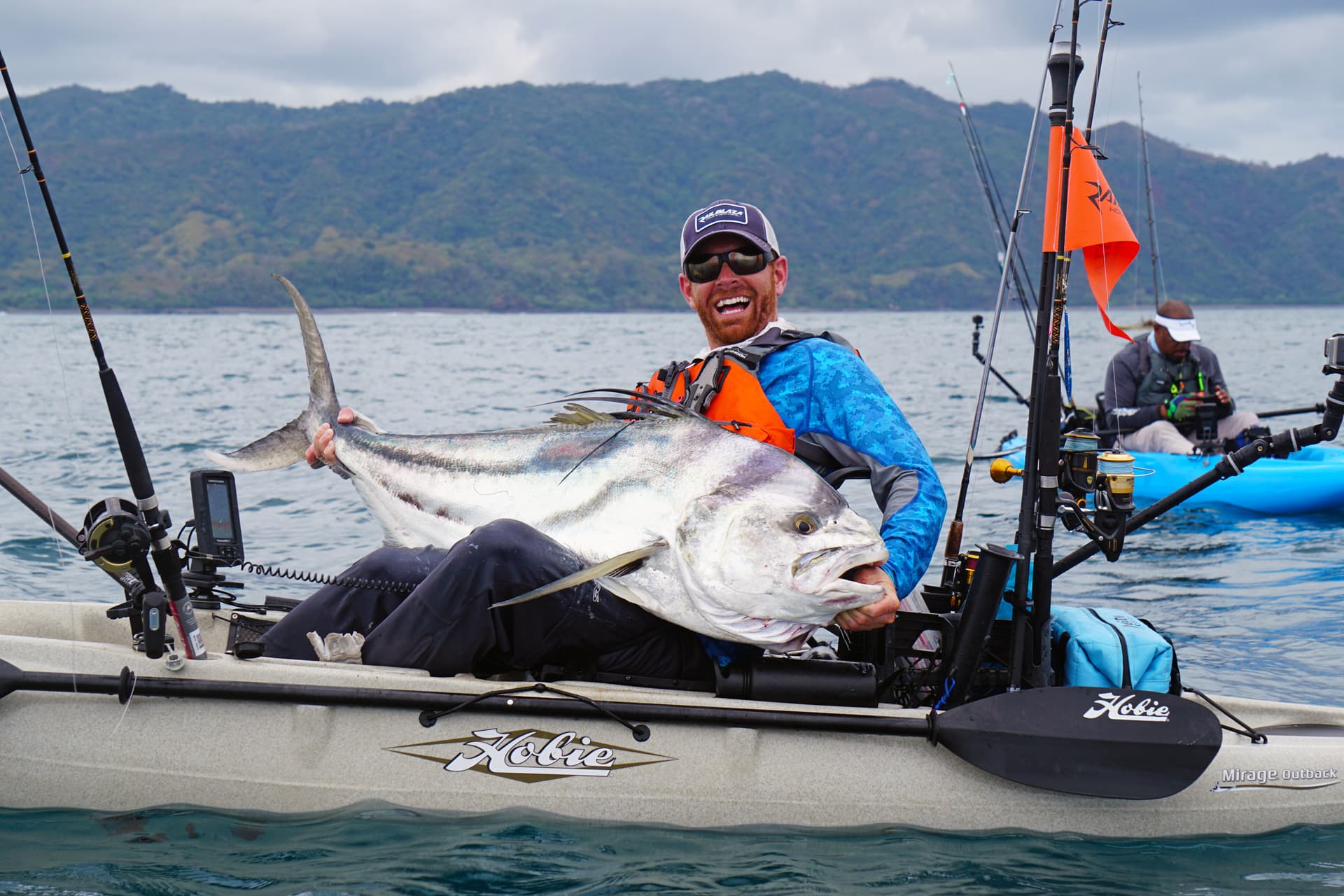Fisherman sits in kayak with big smile, holding large white fish