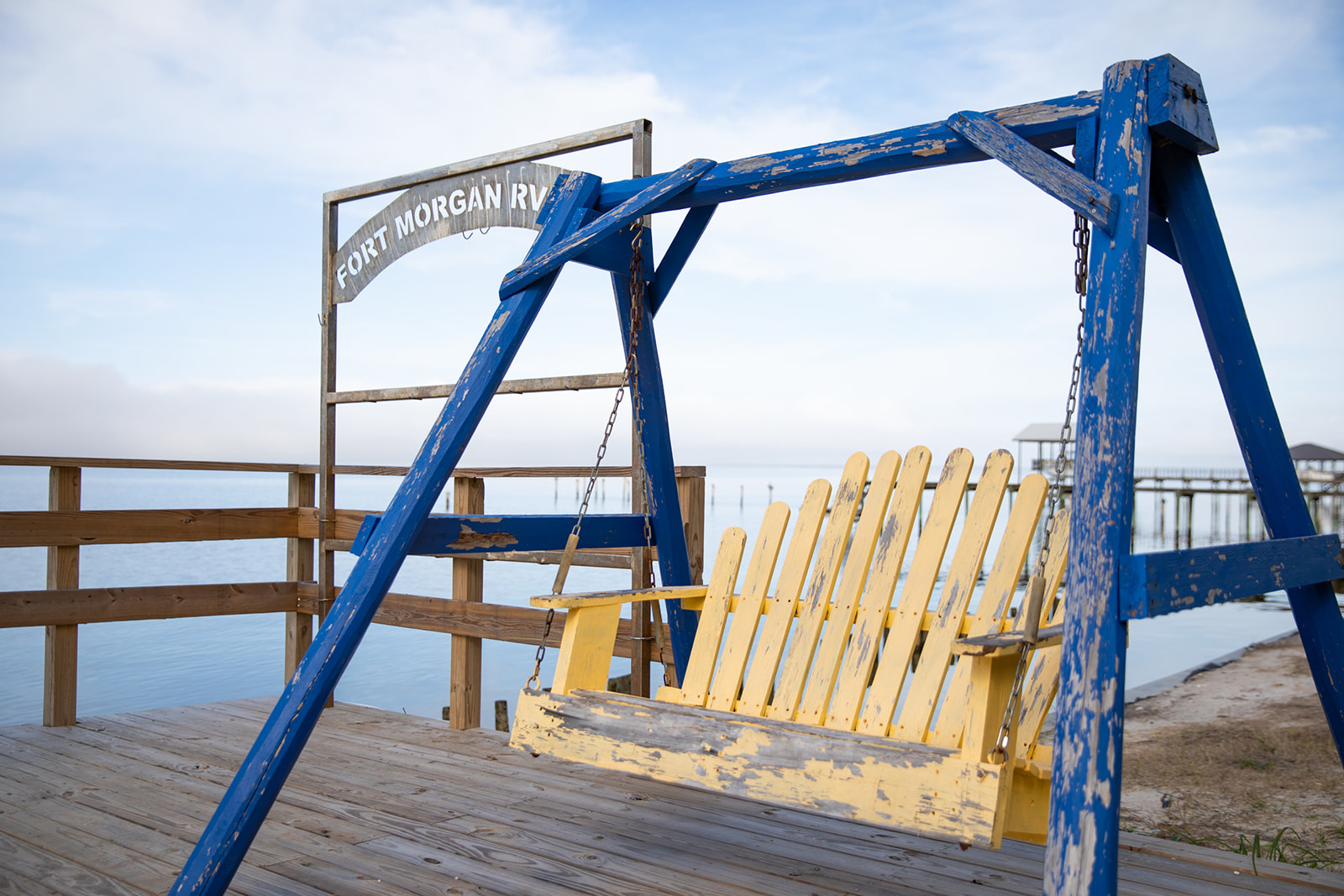 A wooden swing positioned on a dock overlooking the water.