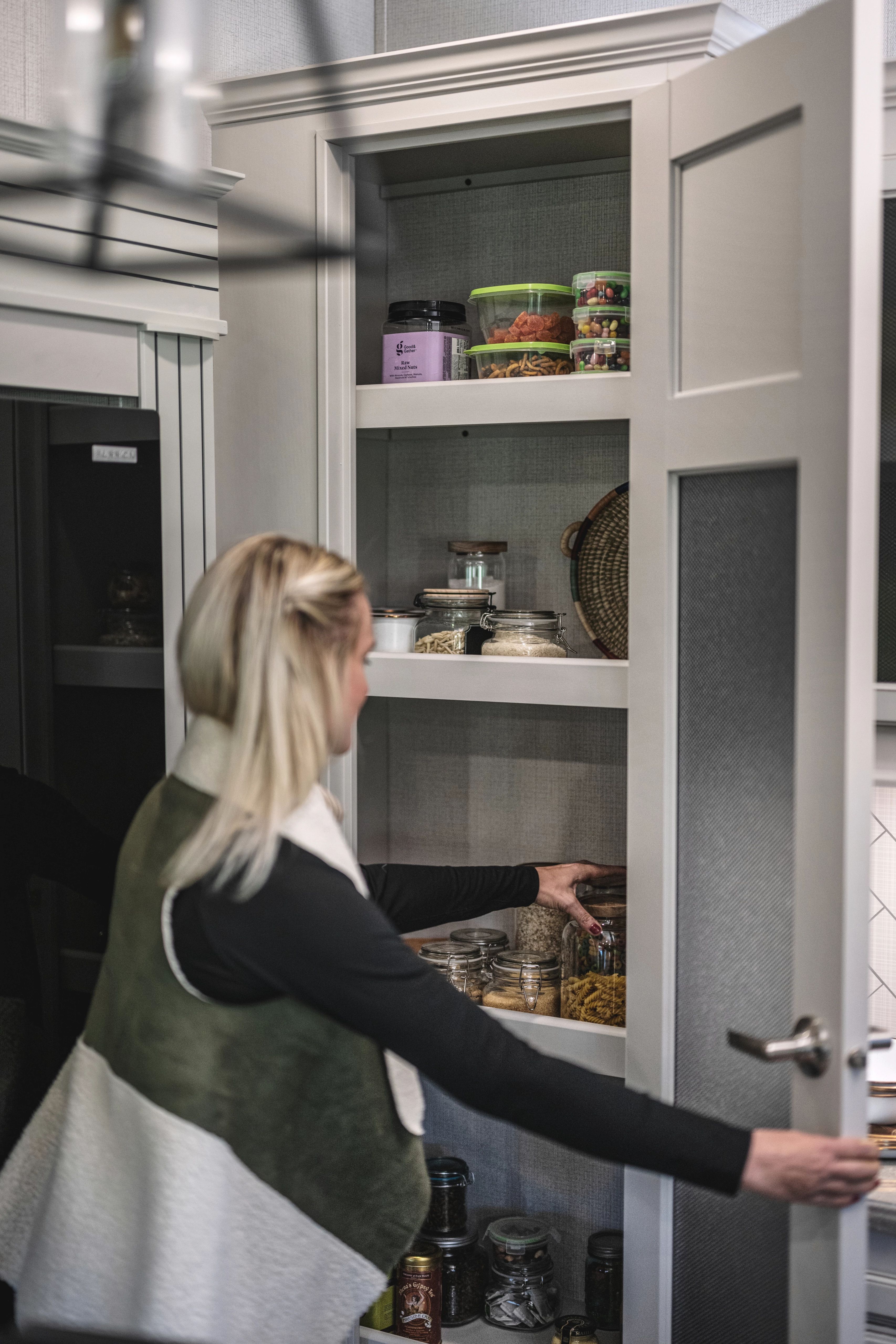 A woman getting a jar of snacks out of a large pantry in a fifth wheel rv
