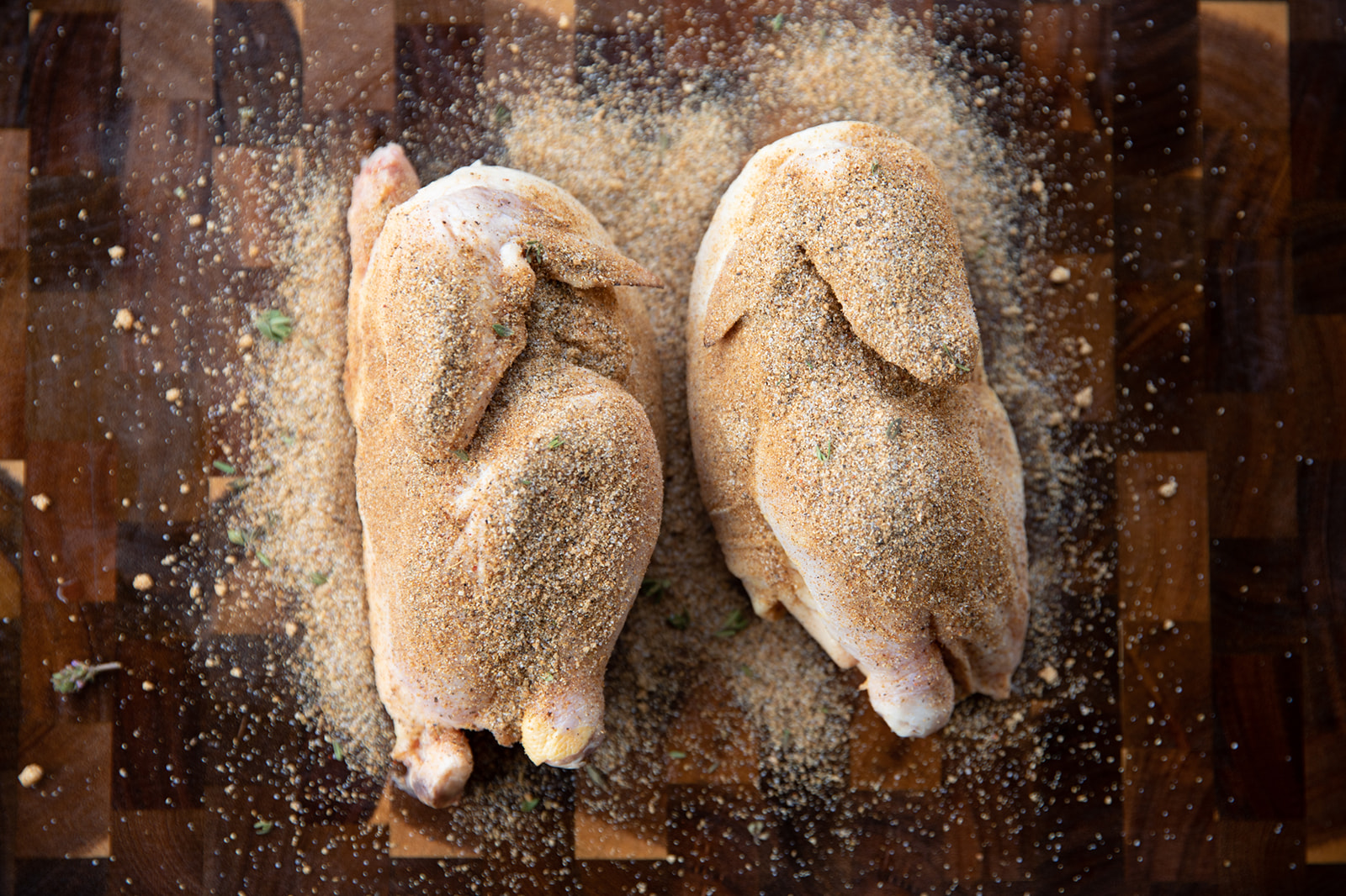 Two halves of a small Cornish hen, dusted with spices.