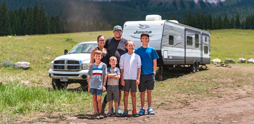 The Renee and Shaun Tilby family and their four kids standing in front of their Jayco Jay Flight in a mountain landscape in Telluride.