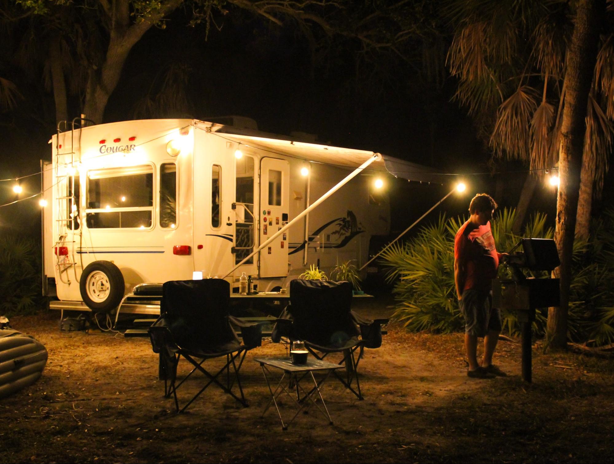 Jesse & Rachael Lyons' cook at a grill at their campsite in front of their Keystone Cougar RV.