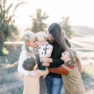 Family portrait of the Thranes looking at one another and smiling, with a field in the background