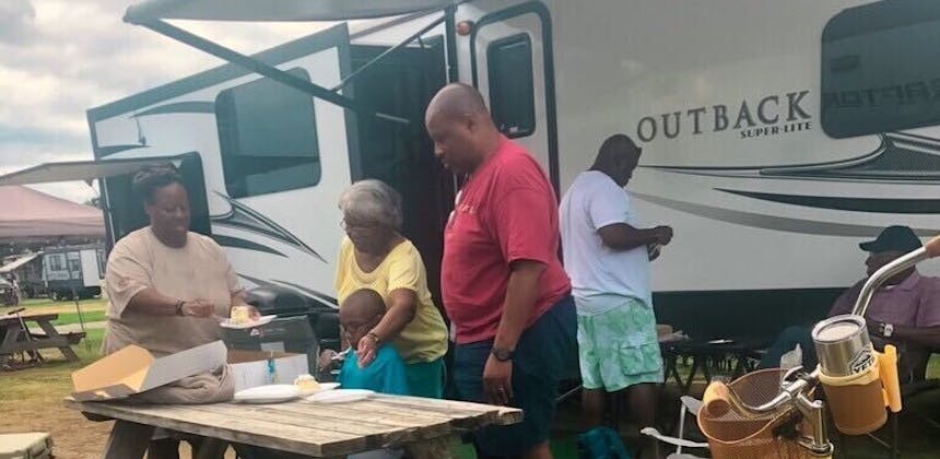 A family sets a picnic table outside of their RV.