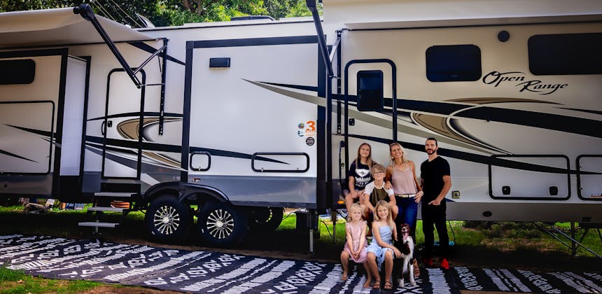 The Cassie and Joshua Bailey family pose in front of their Highland Ridge Open Range Fifth Wheel.