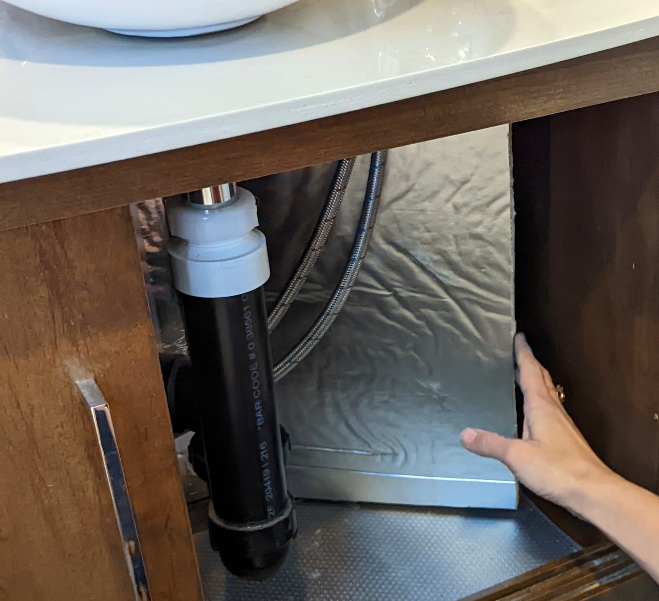 Sarah Bauer putting insulation underneath her kitchen cabinet 