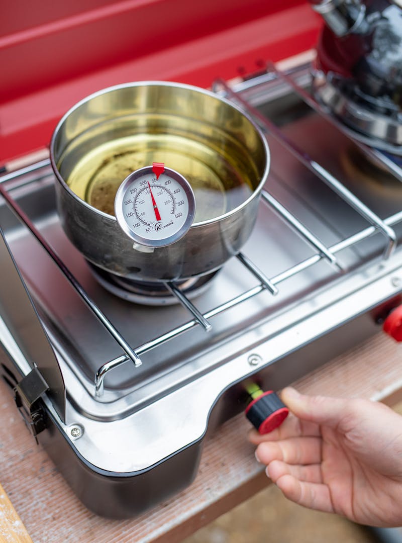 Heating a pot of oil for deep frying on a campsite burner.