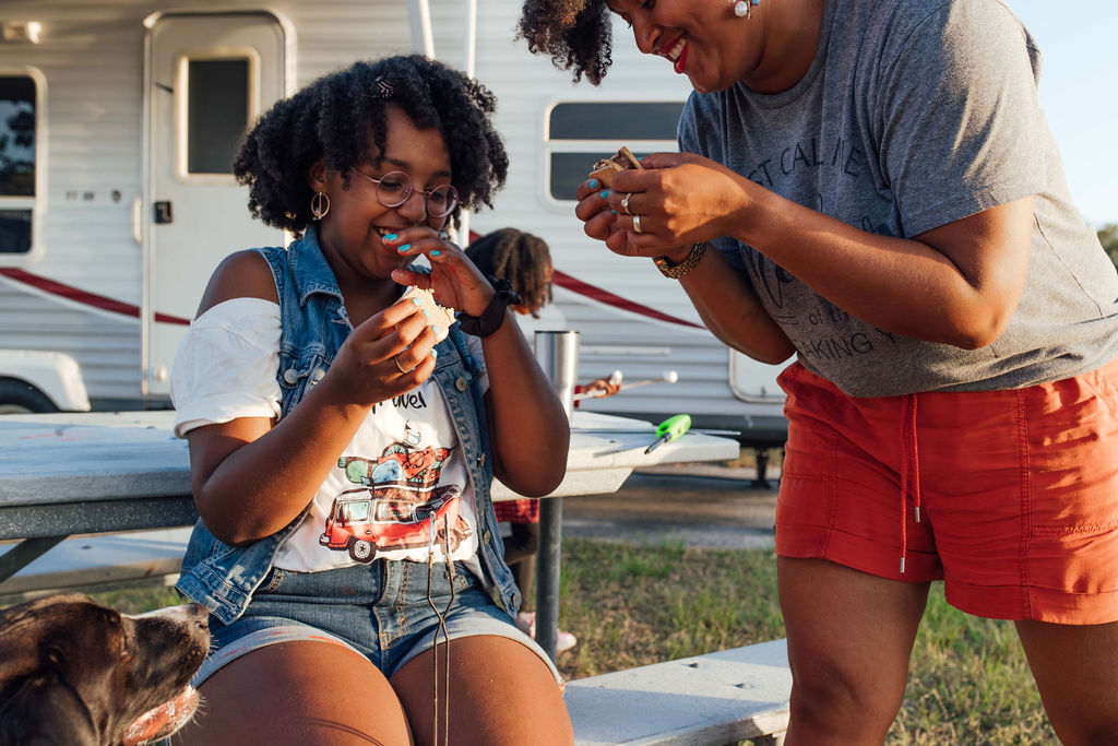 Mom and daughter laughing while eating s'mores. 