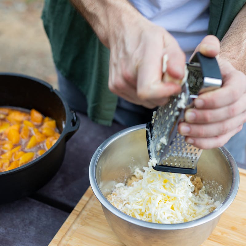 Grating cold butter into a bowl for the cobbler topping.