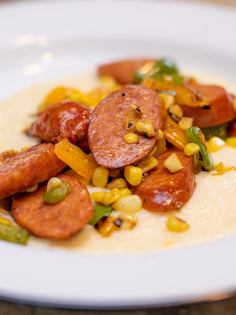 Sausage, corn and cooked peppers over creamy grits.
