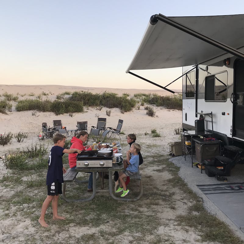 Kids at a picnic table outside an RV.