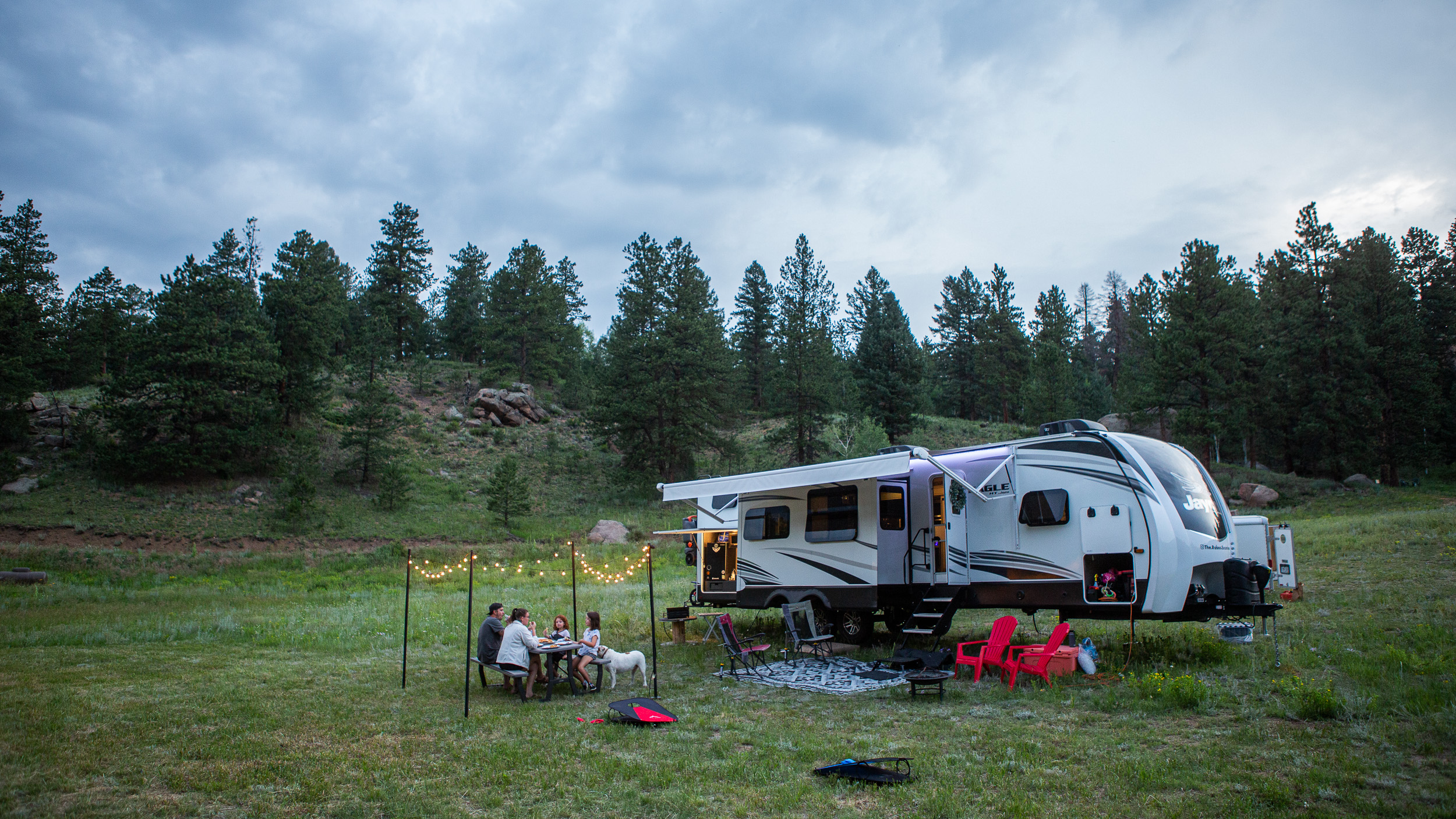 The Roberson family eating dinner on a picnic table next to their Jayco Eagle