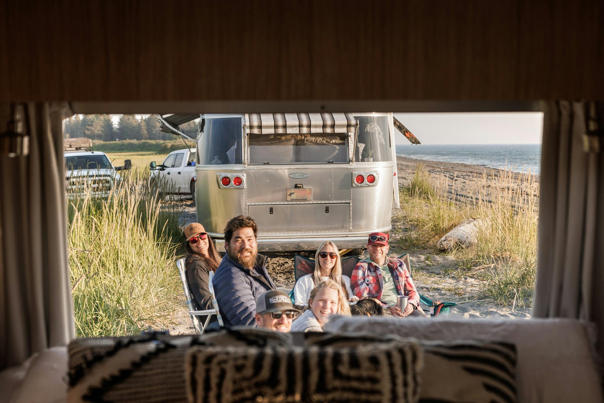 Karen Blue's friends and family smiling for a photo as they sit by the beach by their Airstream RVs