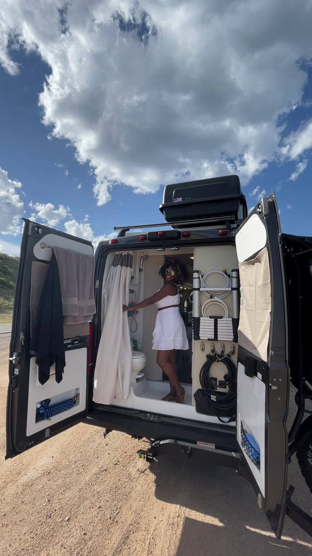 Rocio stands in the bathroom of her Class B with the doors open.