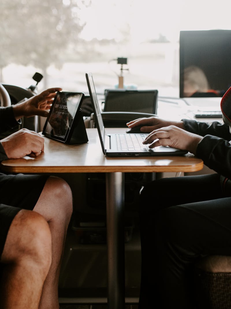 Two people sitting at a desk inside an RV, looking at computer screens.