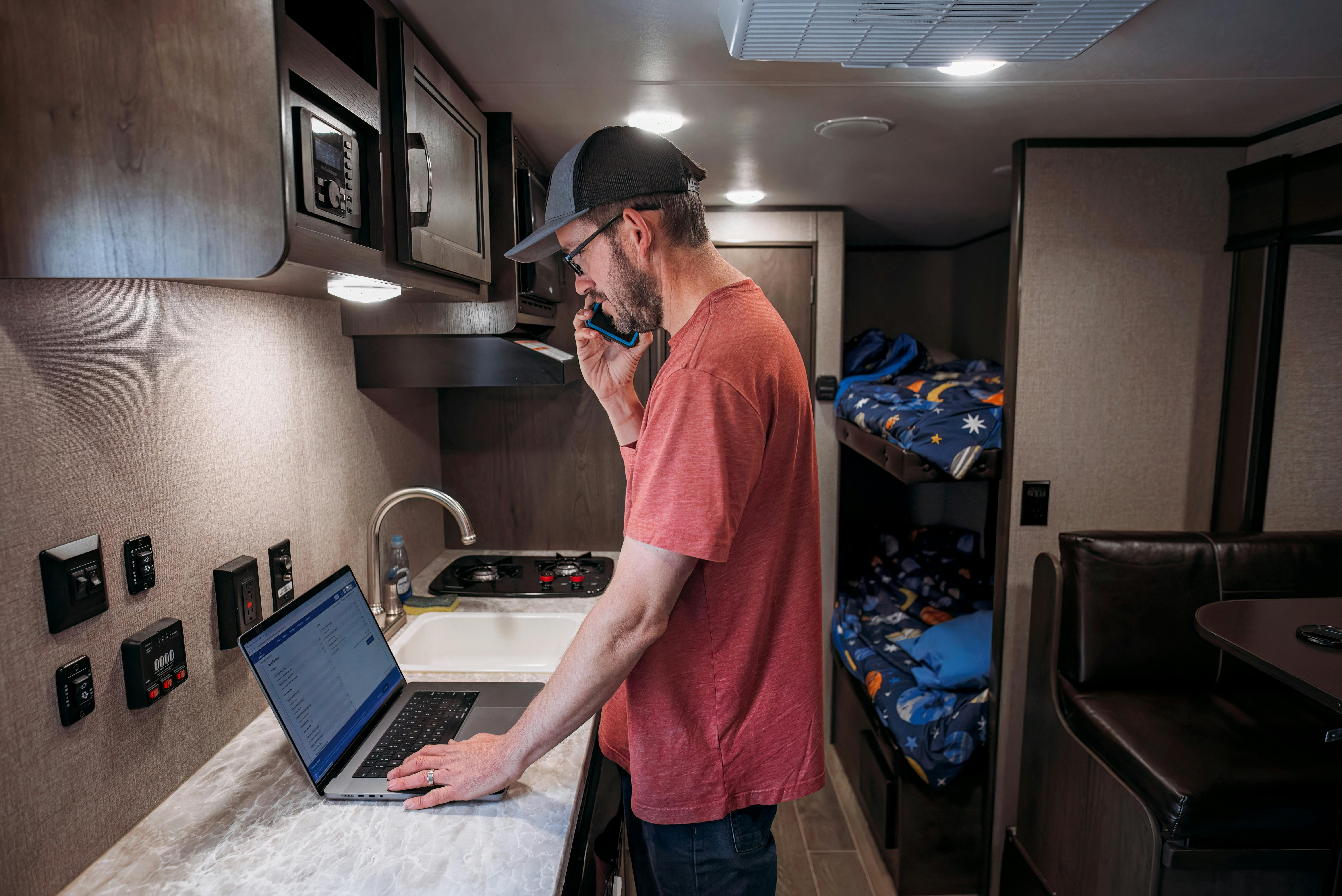 Jason Takacs' on his phone and laptop inside of his Jayco Jay Flight