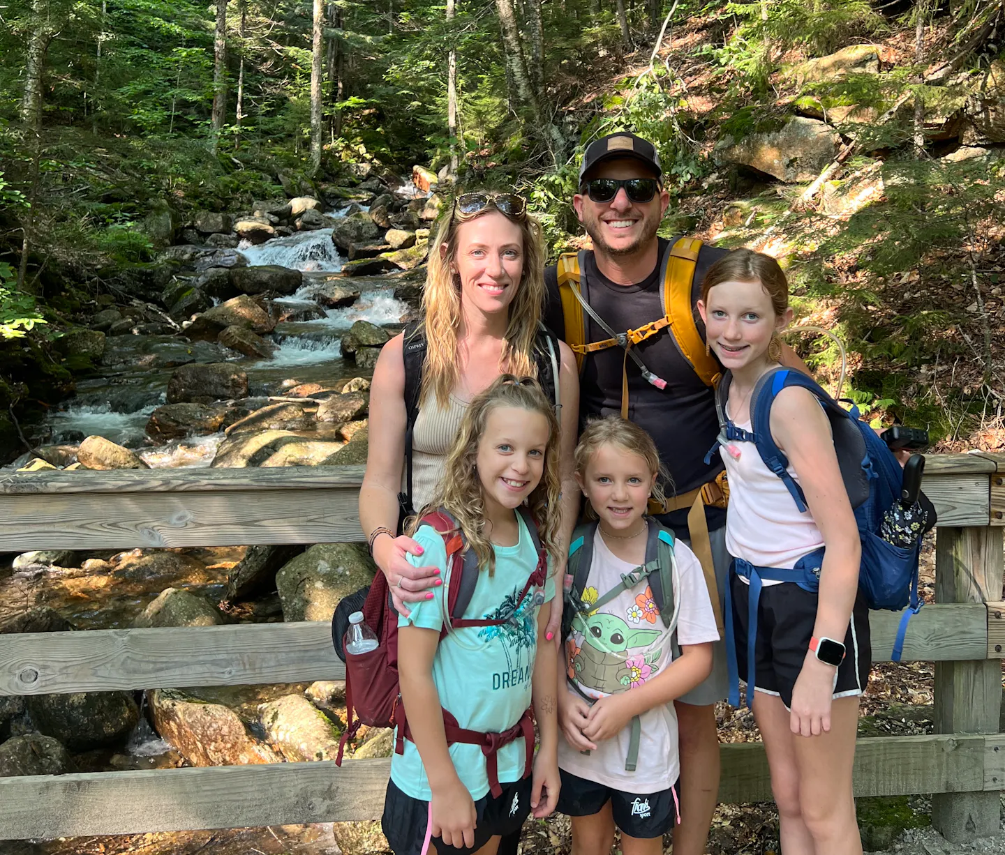 Rob and Ashley Peeples family on a bridge over a mountain stream