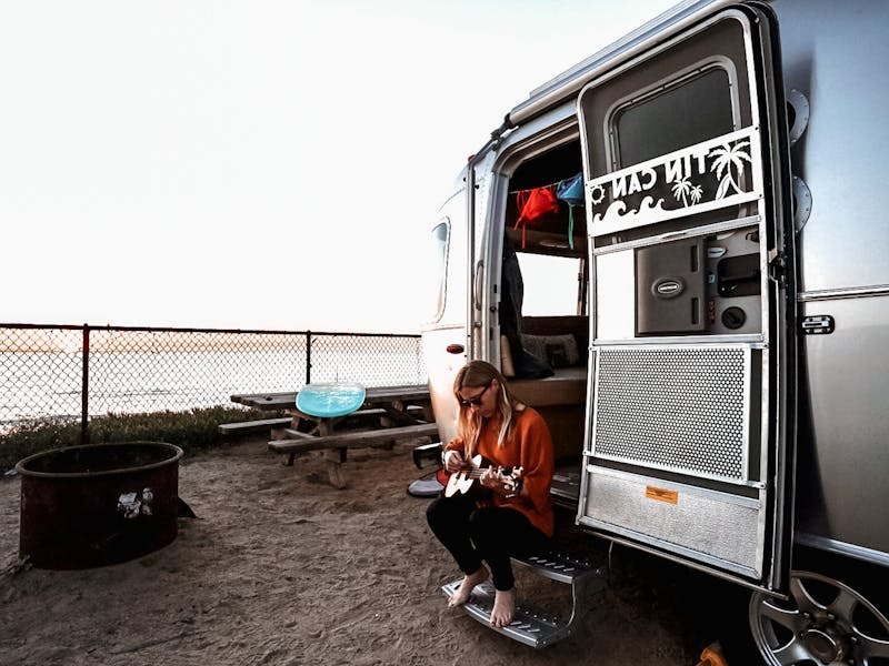 Stacey Powers playing the ukulele in the door of her Airstream