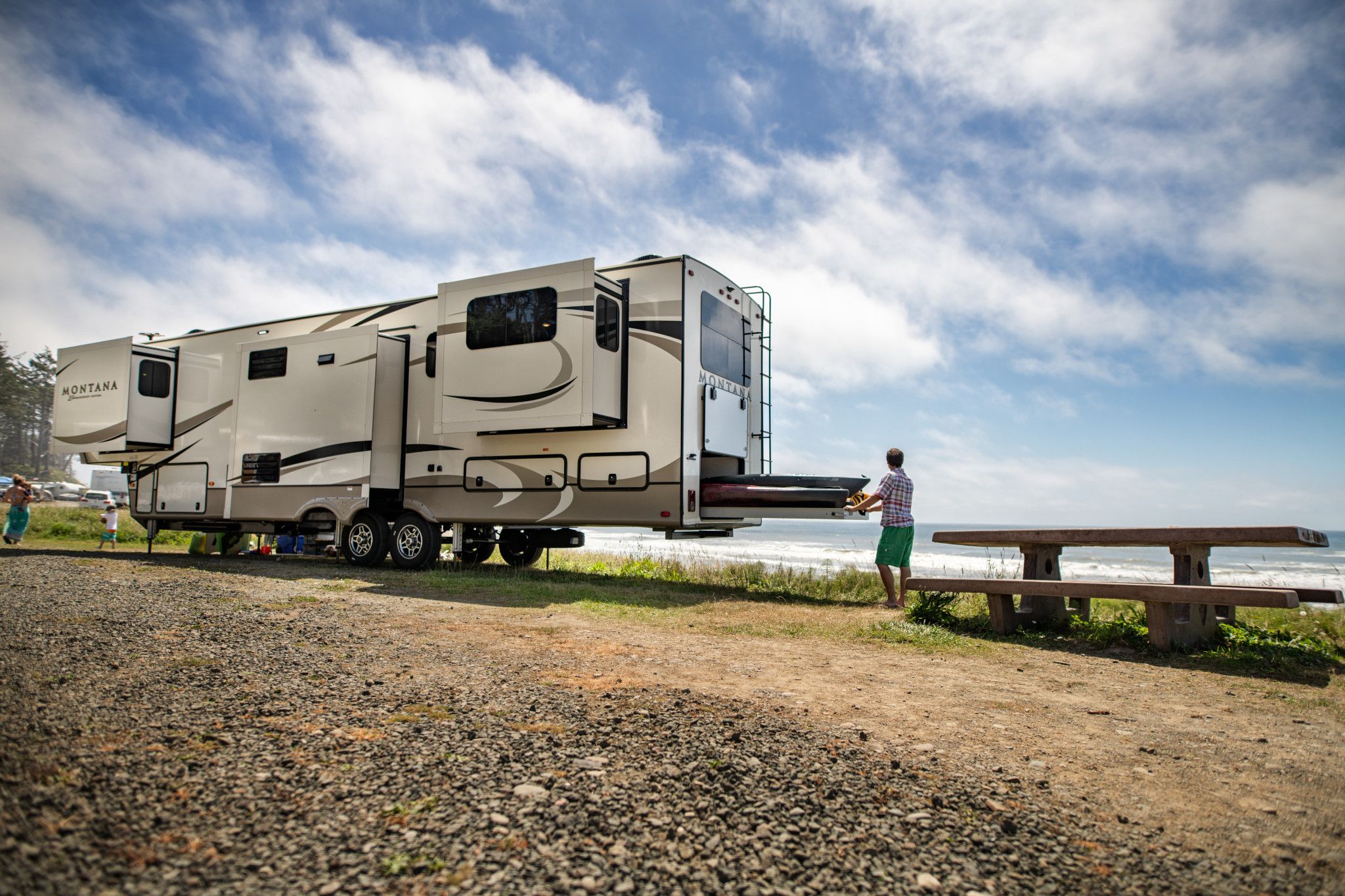 A man pulling kayaks out of storage from a keystone Montana fifth wheel rv
