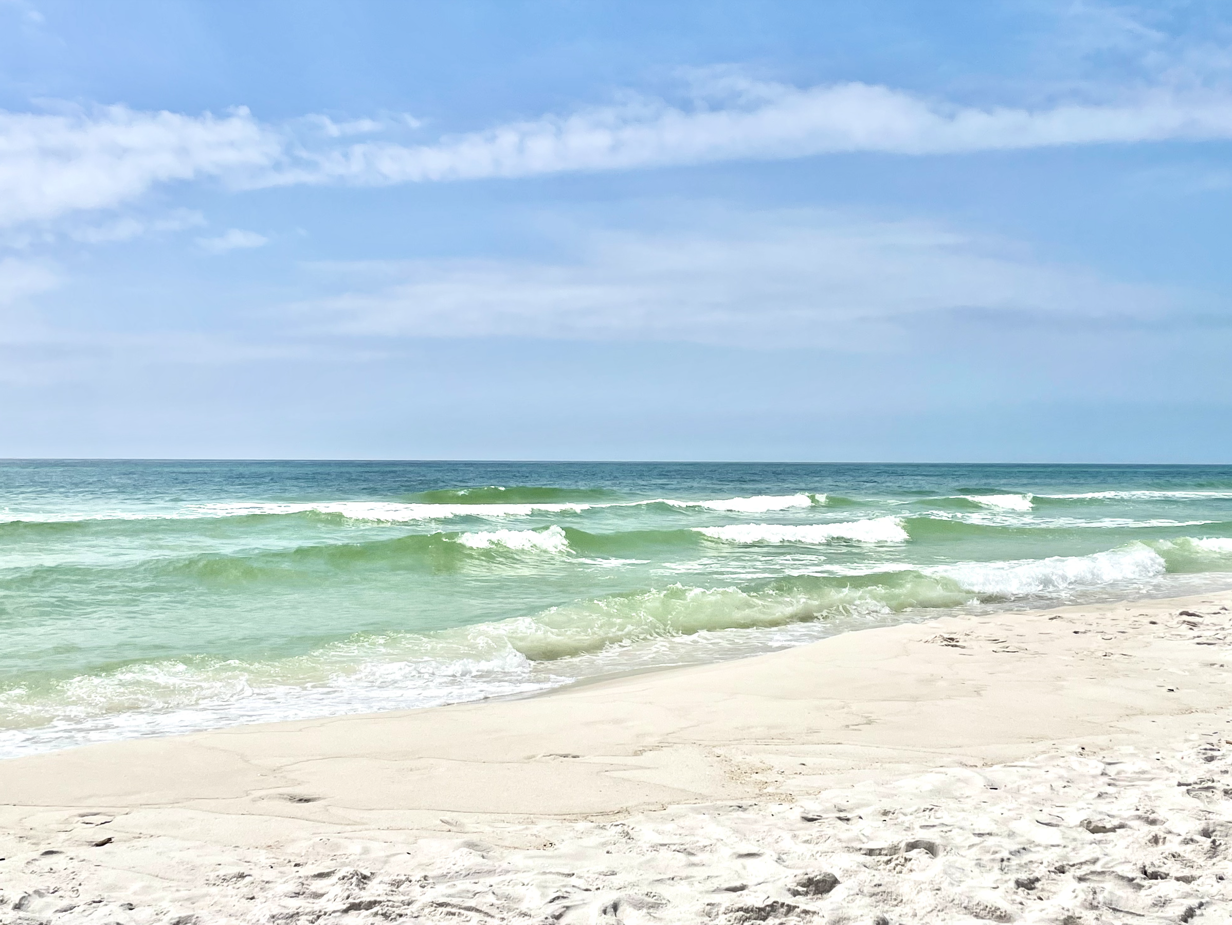 A beach with sand and blue skies at Fort Pickens in Pensacola, Florida.