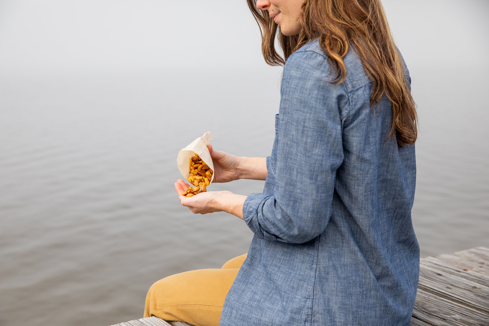 Aubrey eating mixed nuts on a dock while dangling her feet in the water.