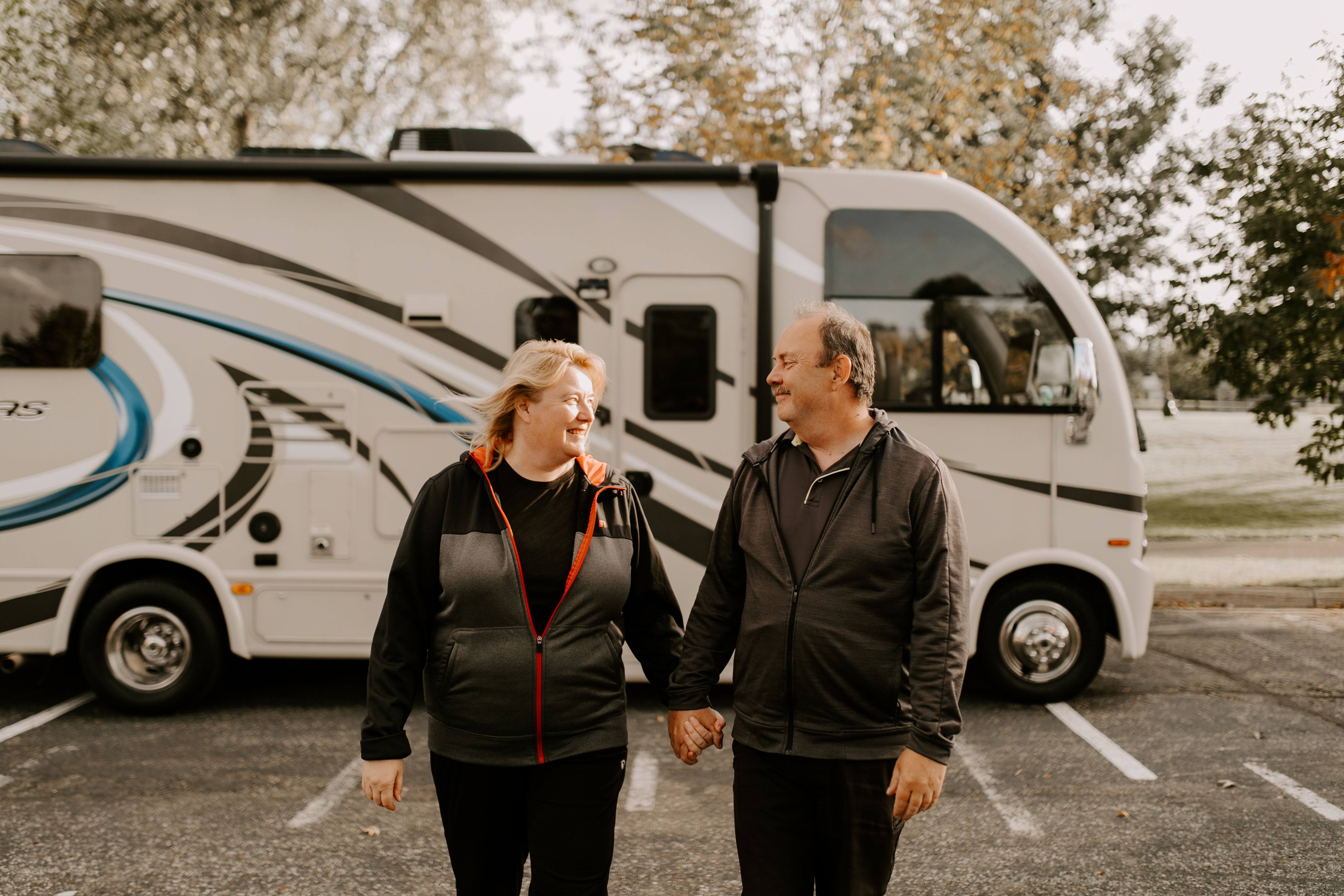 A couple holding hands in front of an RV.