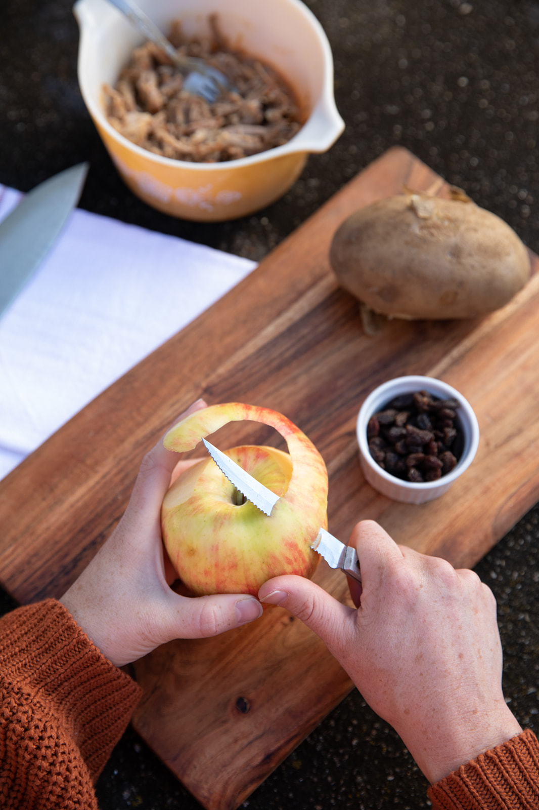 Two hands peeling an apple.