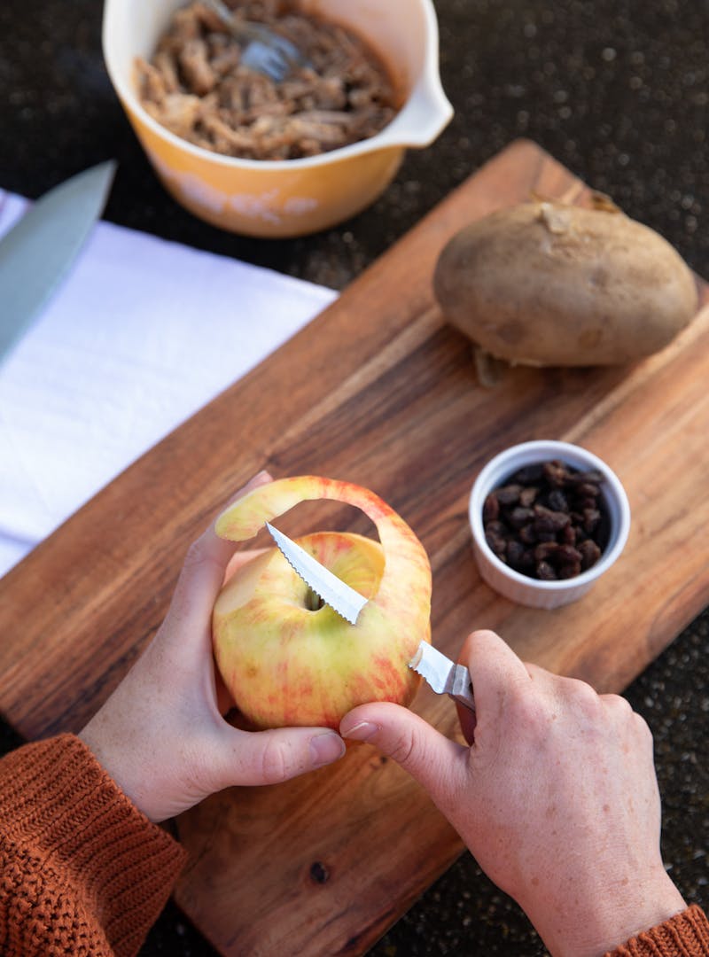 Two hands peeling an apple.