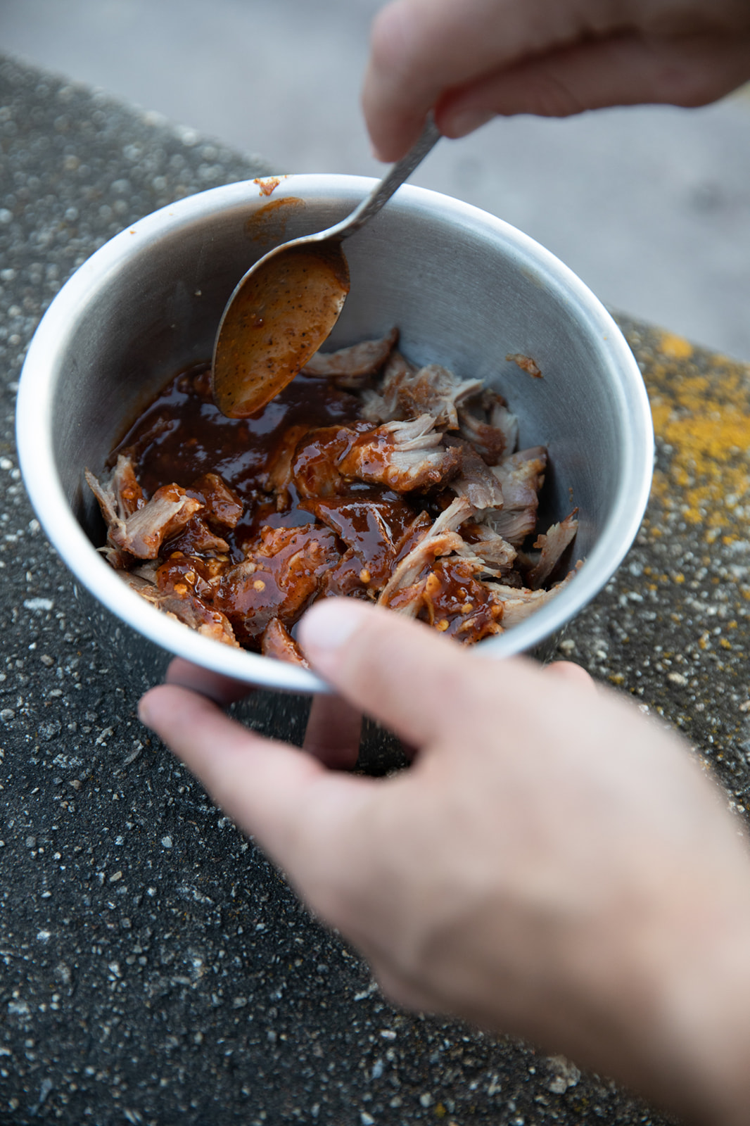 Pulled pork in a bowl gets mixed with barbeque sauce.