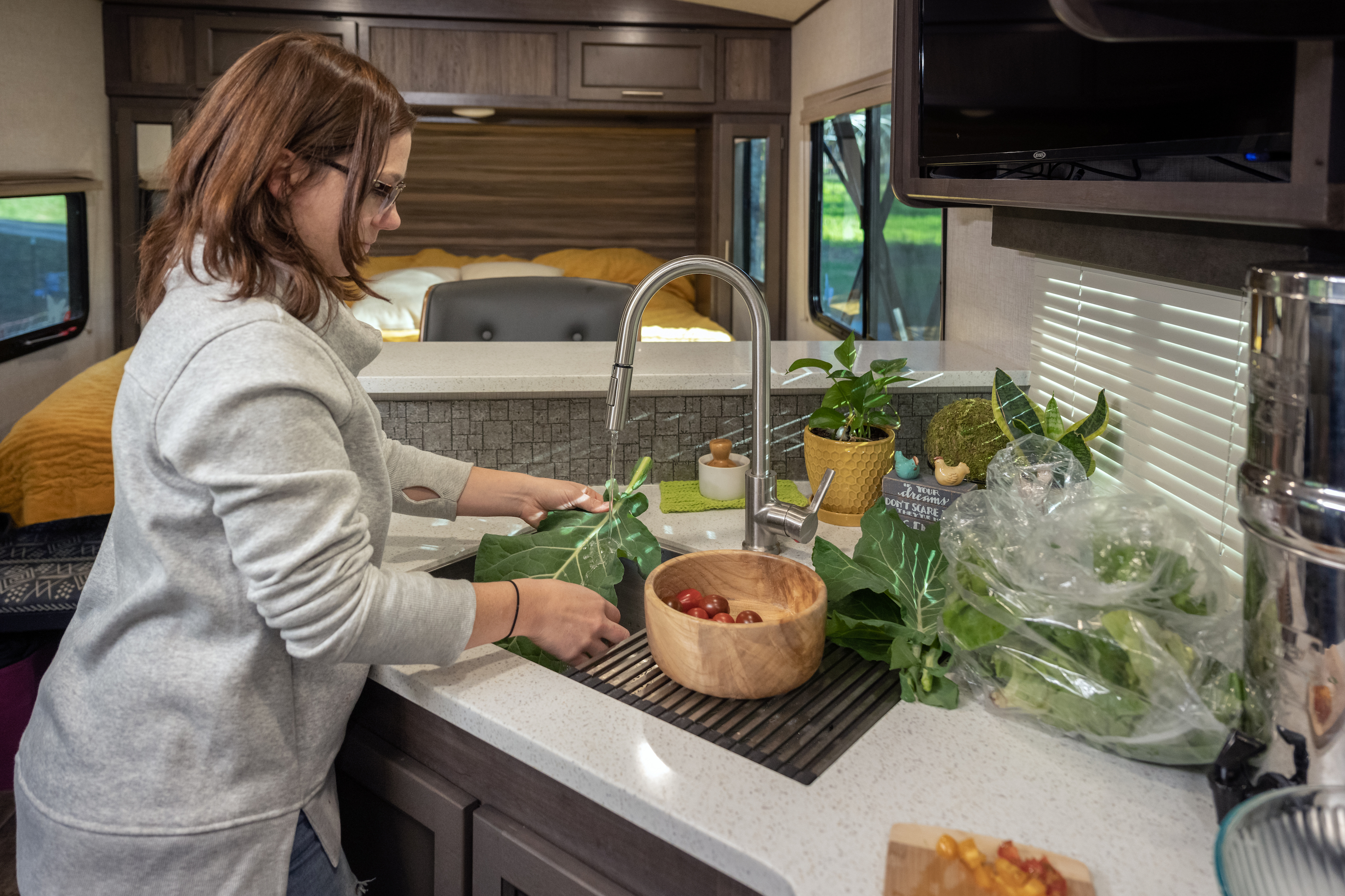 Marcia Schabel cleans fresh produce that she harvested at the sink inside her Sunset Trail RV.