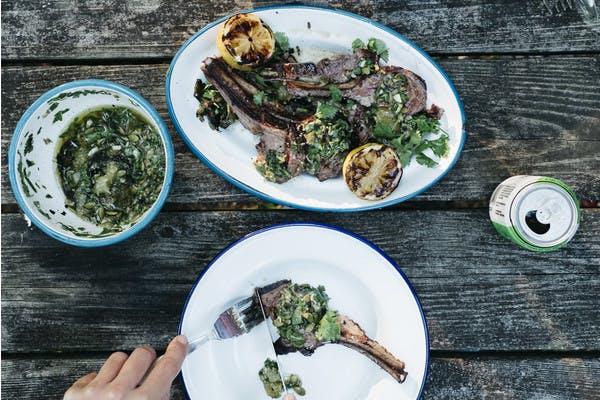 A plate of lamb with lemons and tomatillo sauce over the top.