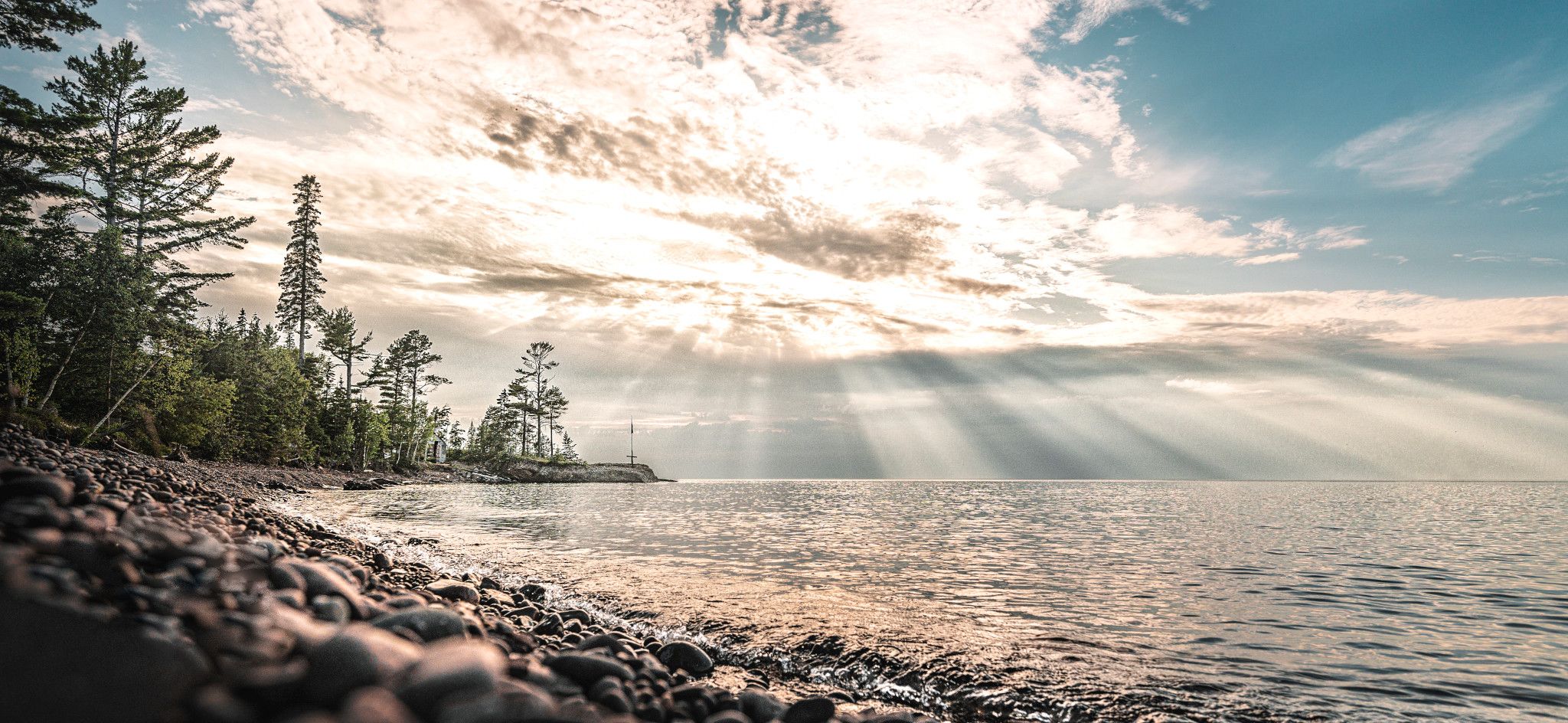 Sun shining over a like with a rocky shore