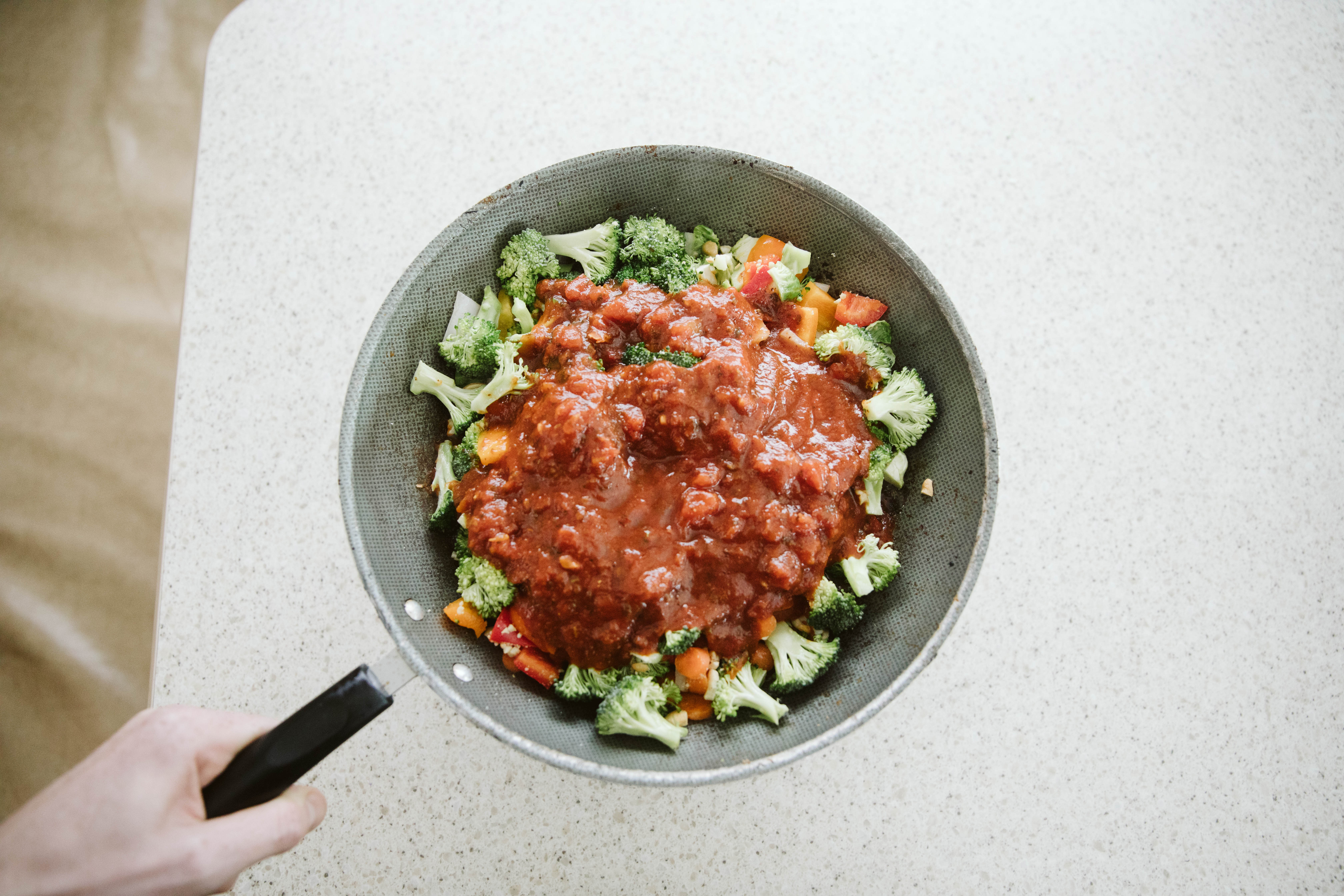 Frying pan full of cooked vegetables and red pasta sauce