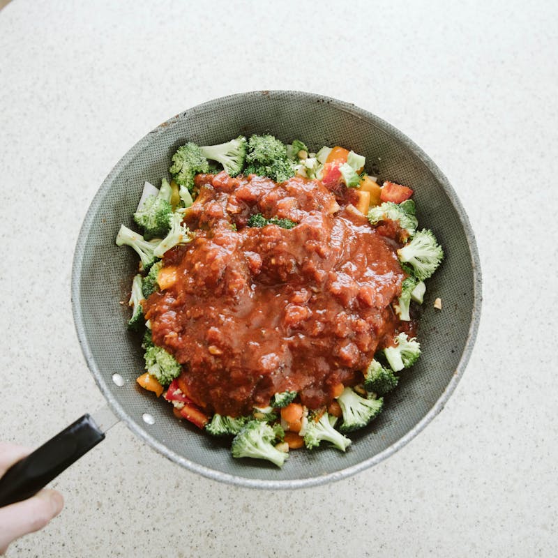 Frying pan full of cooked vegetables and red pasta sauce