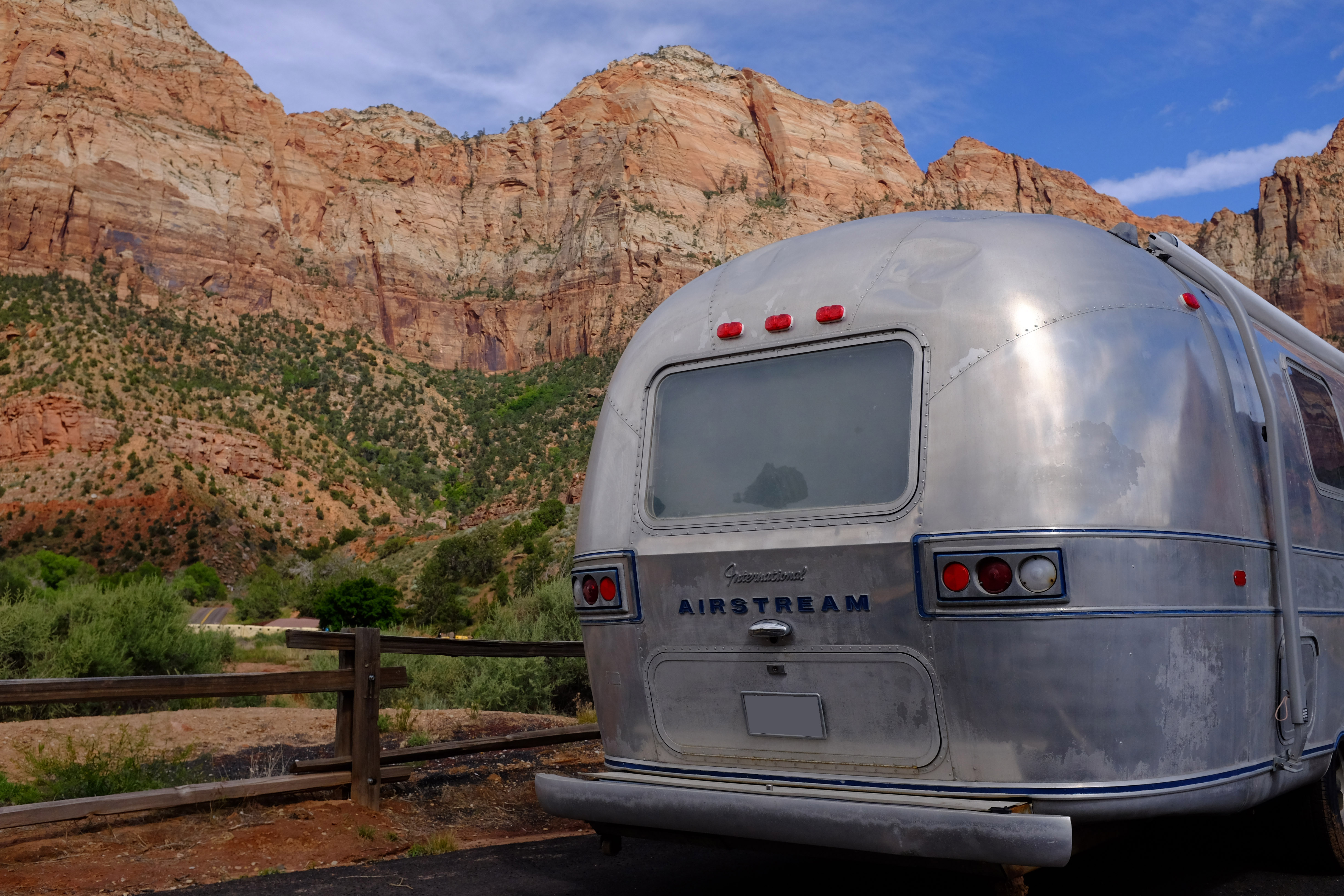 A vintage Airstream trailer parked alongside rocky outcroppings.