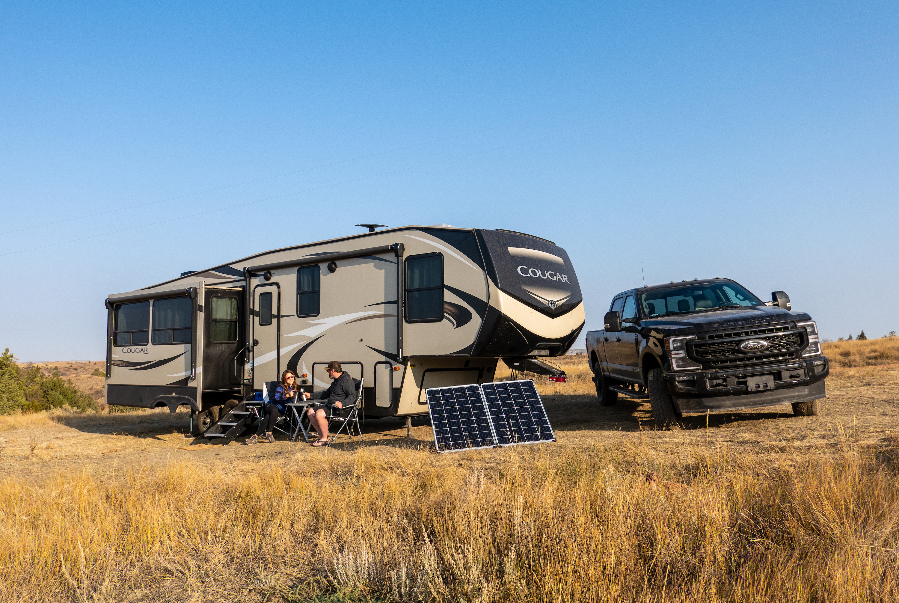 Cindy Scott and her husband sit outside of their RV with solar panels. 