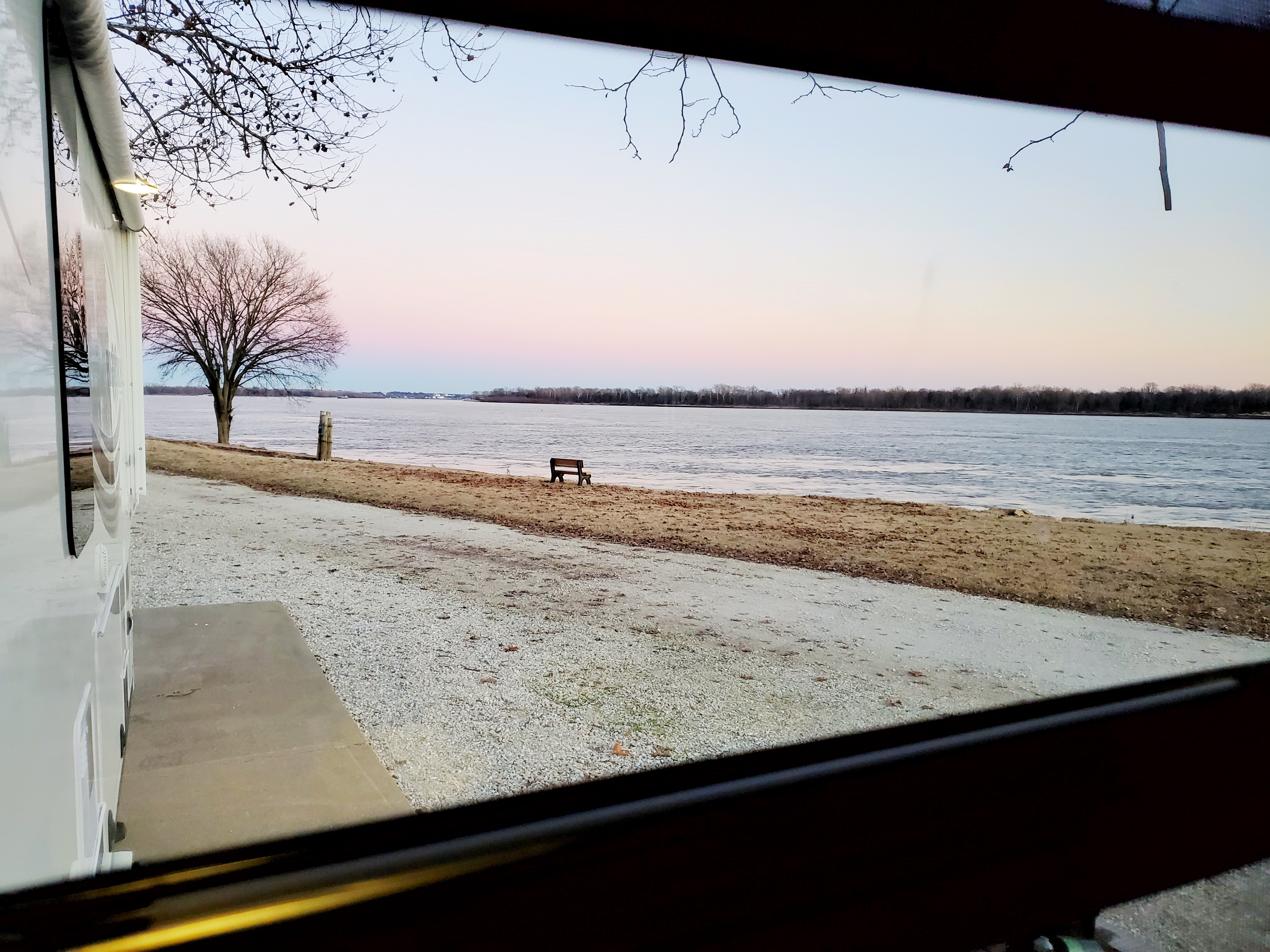 A photograph out an RV window onto a wintry lake.