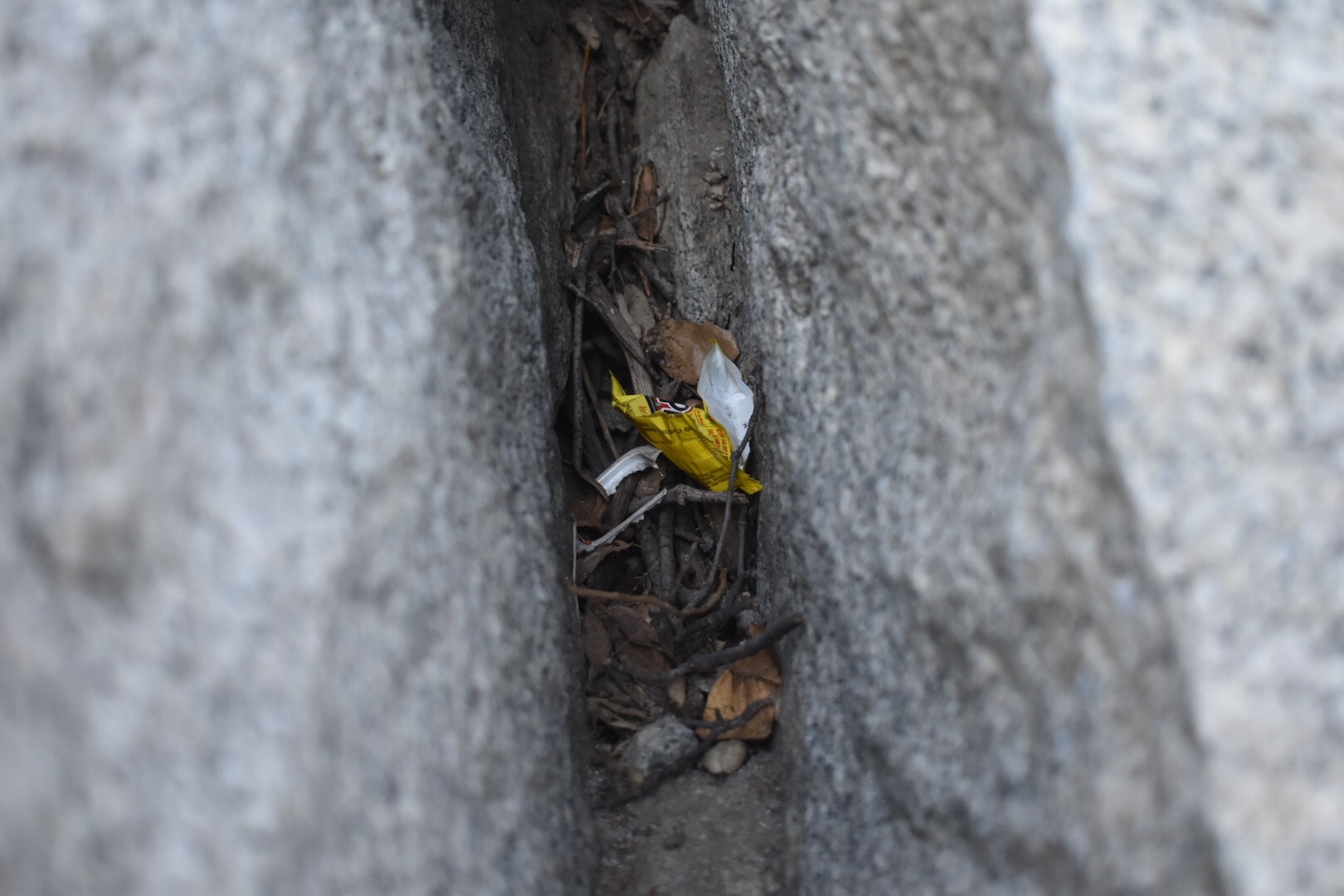 Piece of yellow trash hidden within two rocks