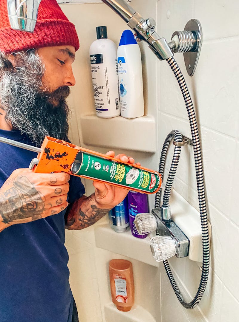 Justin Russell caulking his bathroom shower
