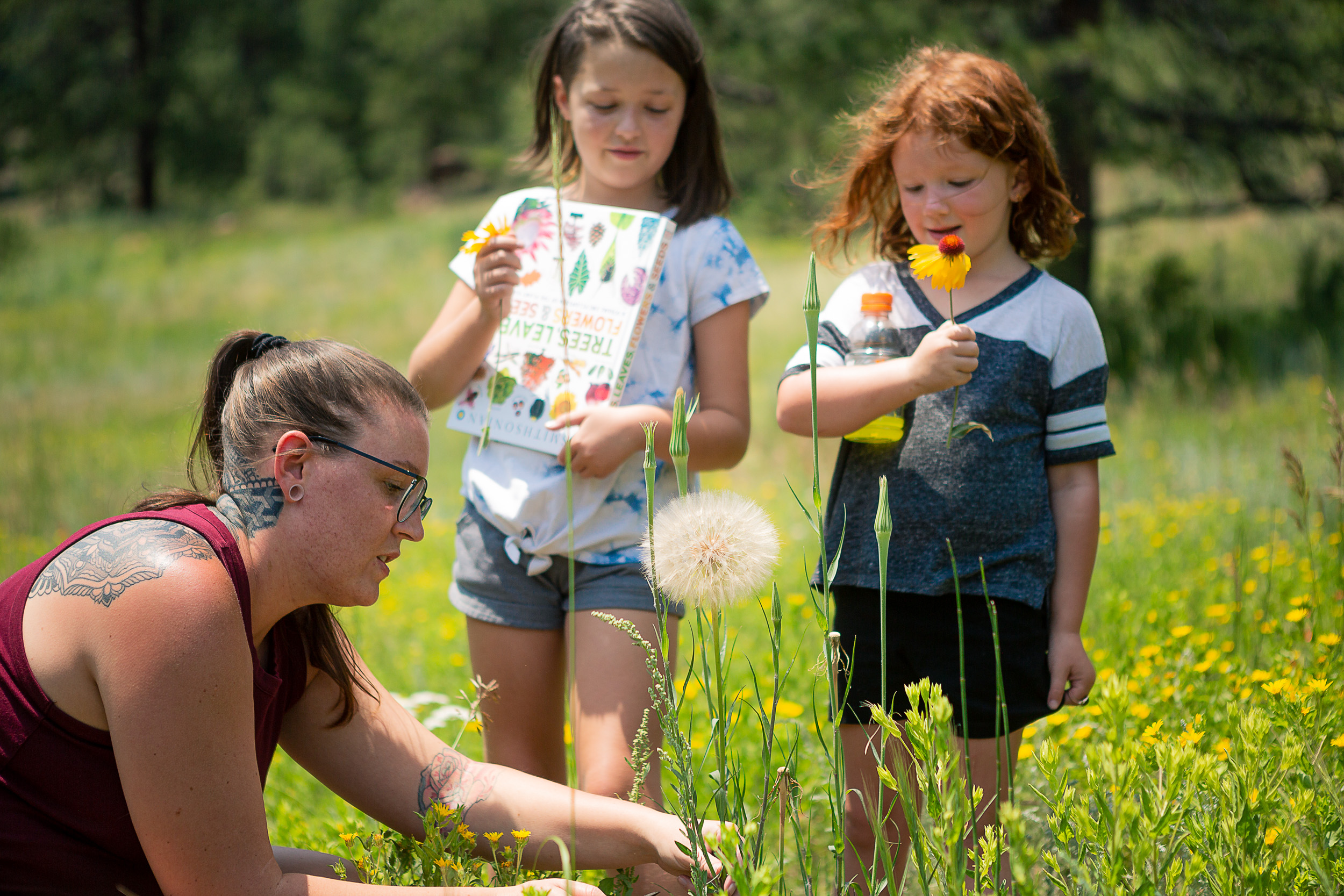 Katy Roberson points at a flower with her daughters watching