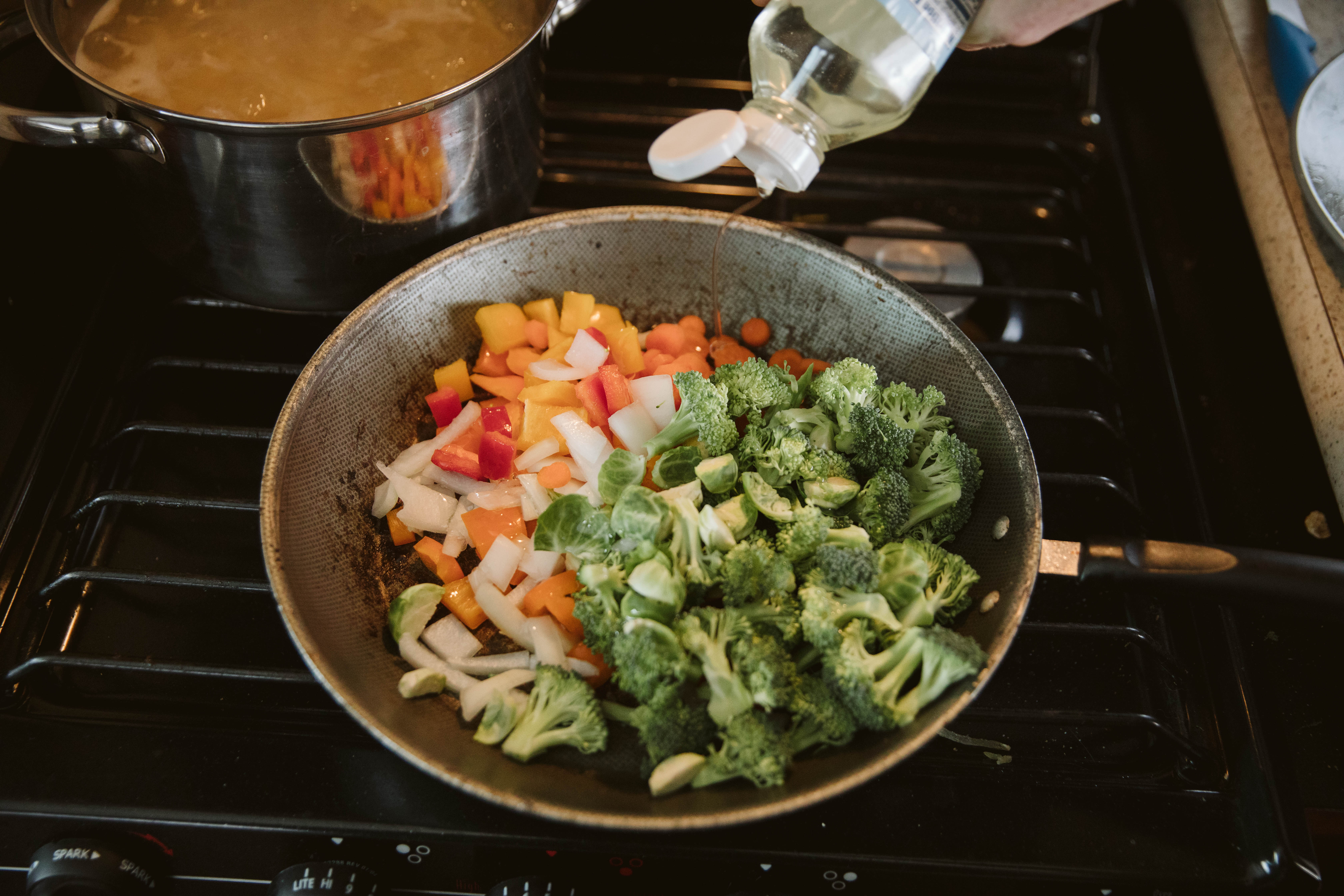 A saute pan full of cooking vegetables.