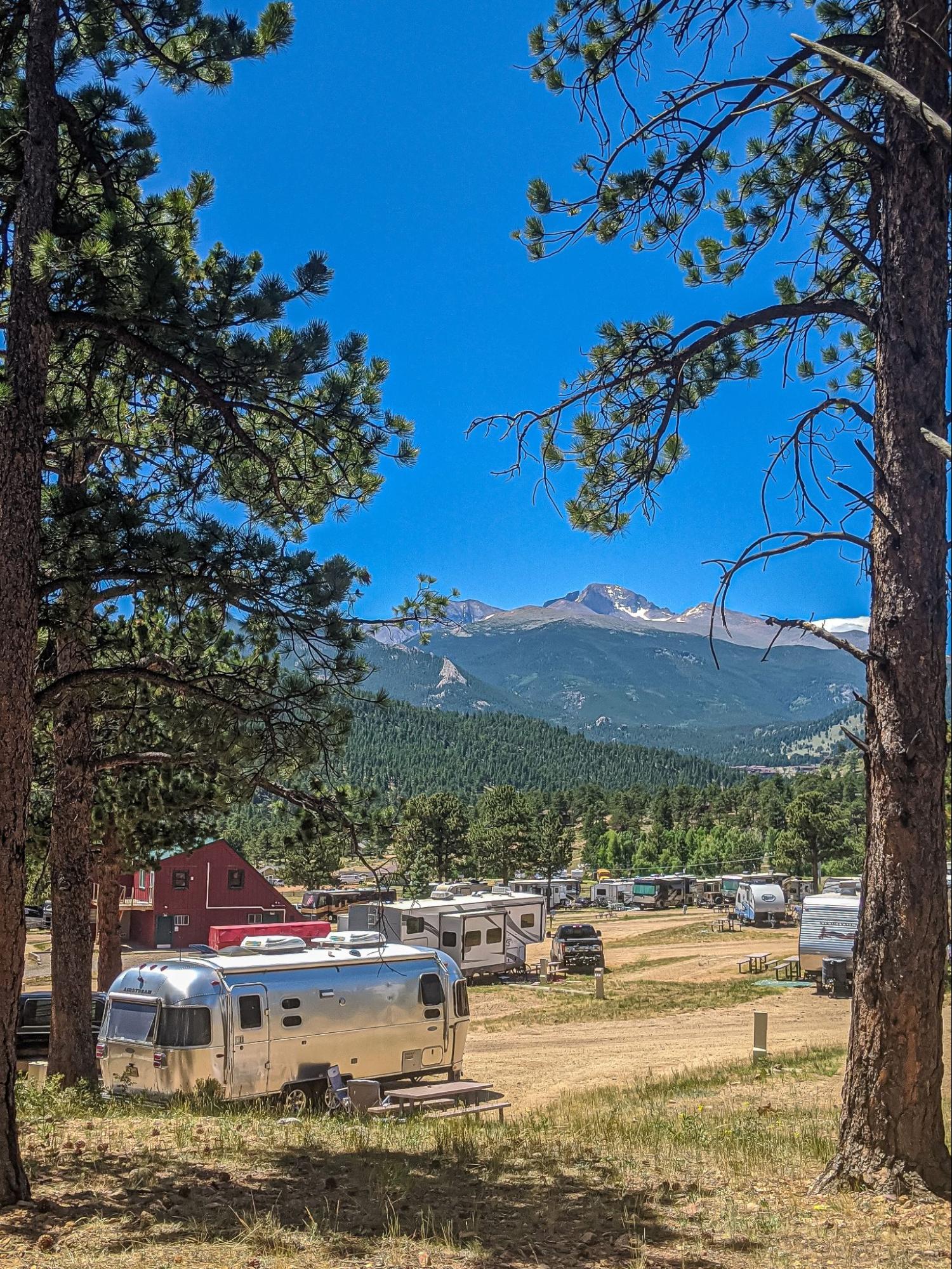 A campsite with multiple RVs parked in front of a mountain landscape.
