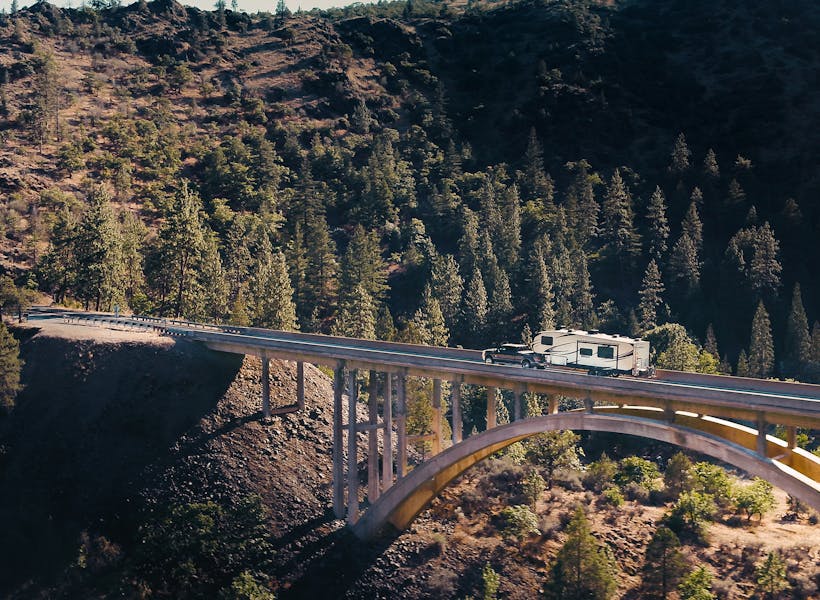 A fifth wheel RV driving across a bridge.