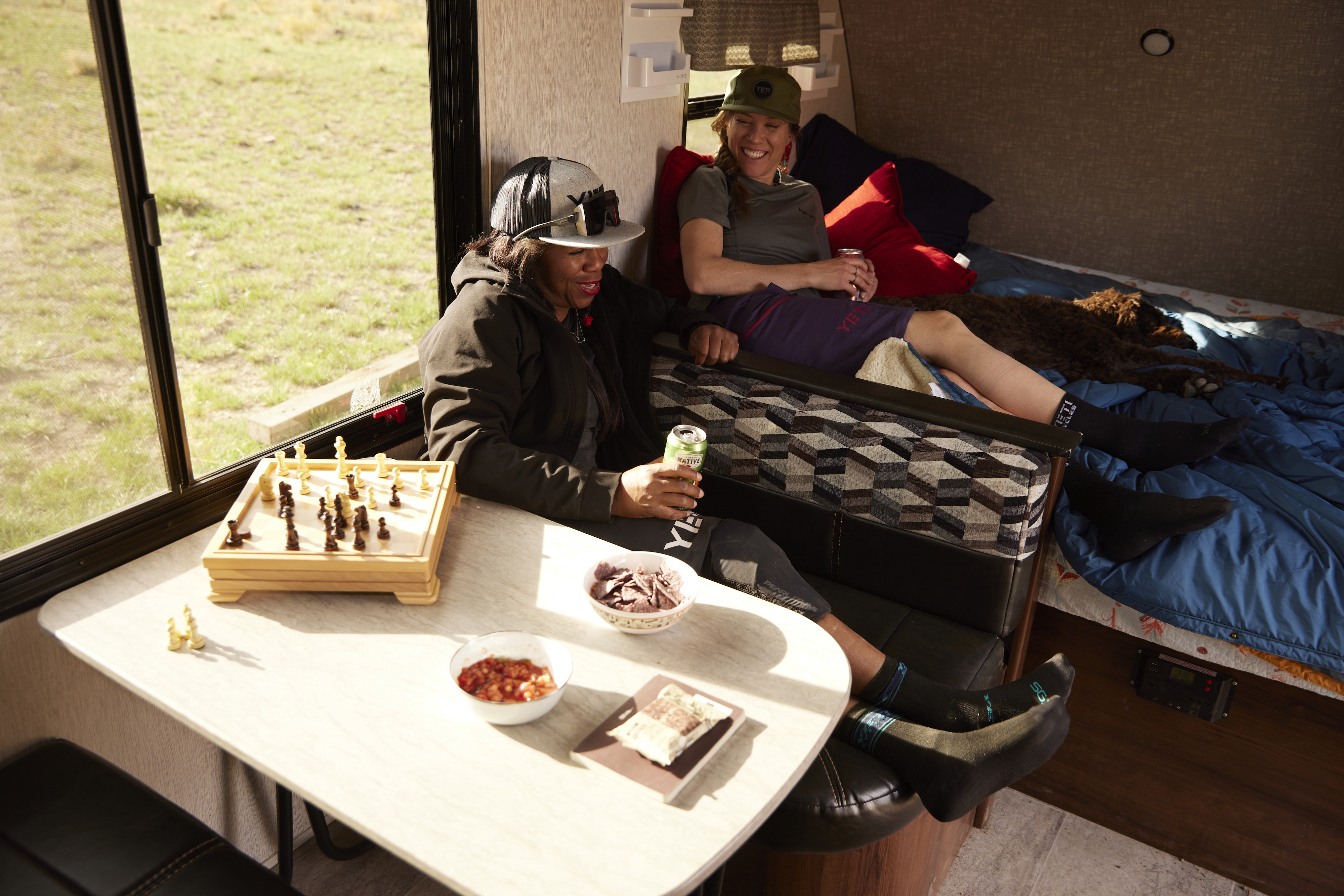 Britt Greer and Brooke Goudy lounge inside of a Mallard travel trailer